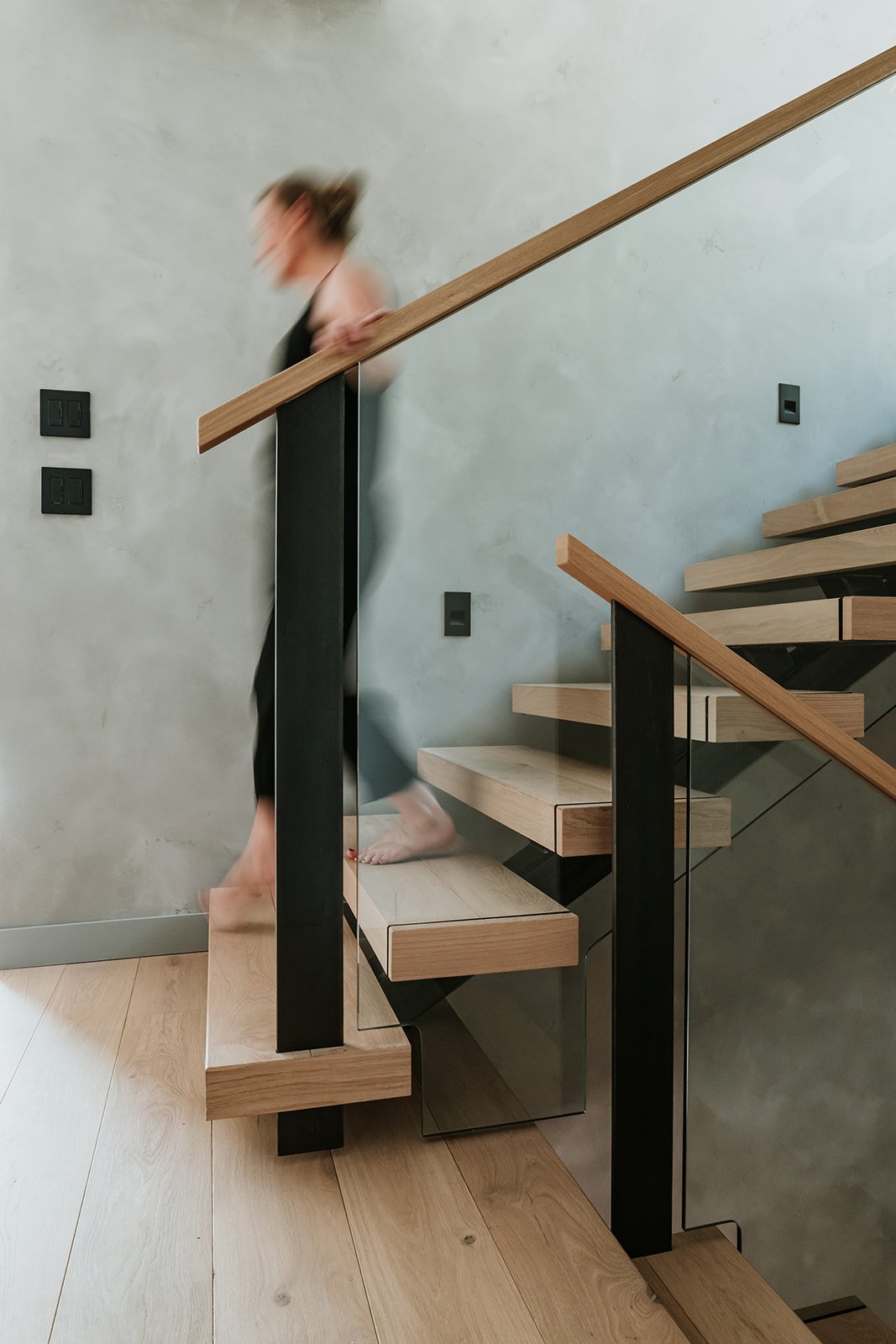 Sunstone Custom staircase with wood caps hiding stanchions, glass panels, black metal fin posts — new-build interior design in Pemberton, BC by LRD Studio. Photography by Darby Magill.