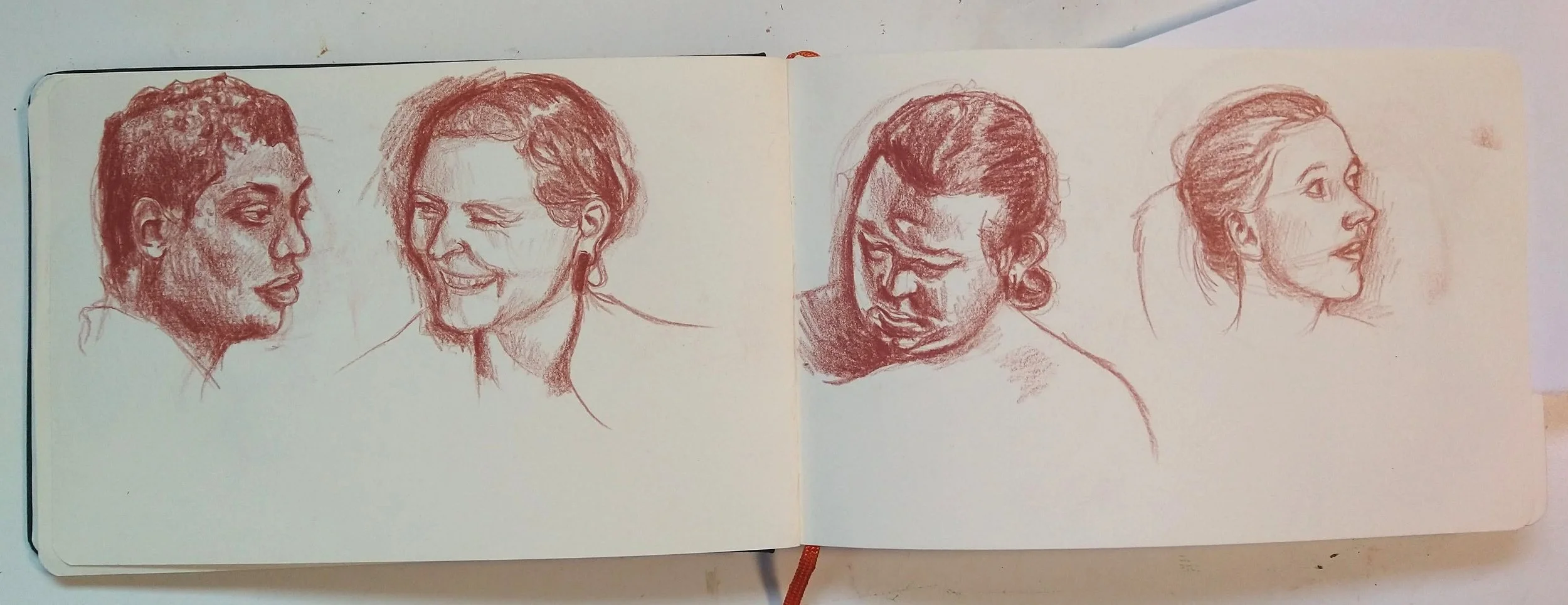 Drawings of heads in sienna colored pencil on two sketchbook pages.