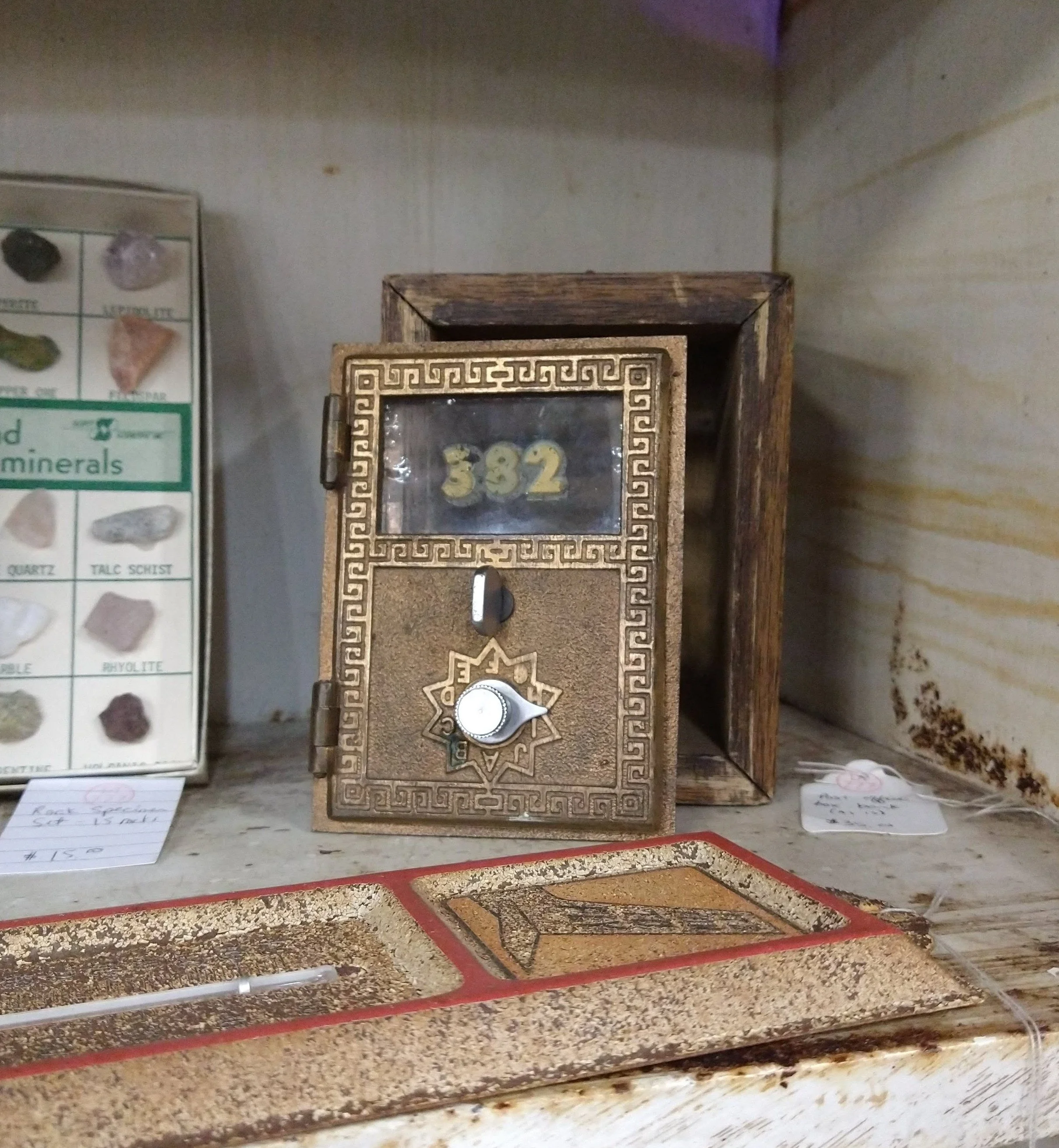 Antique post office bank box on a shelf.