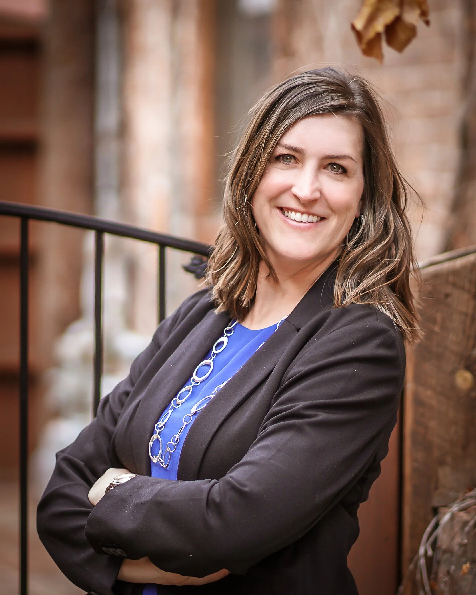 A photo a a brown haired woman in a black suit coat and blue shirt