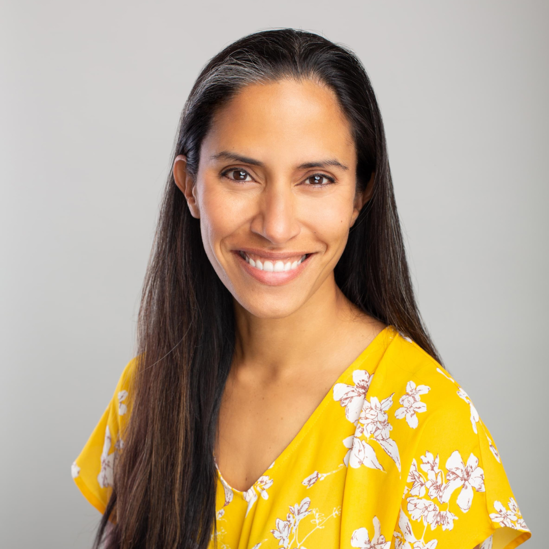 A woman with black hair poses in a yellow dress