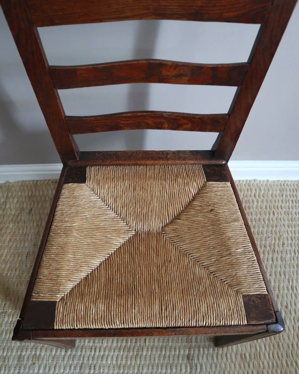 Pair of sculptural rustic oak ladder back dining chairs with rush seats, circa 1930s.