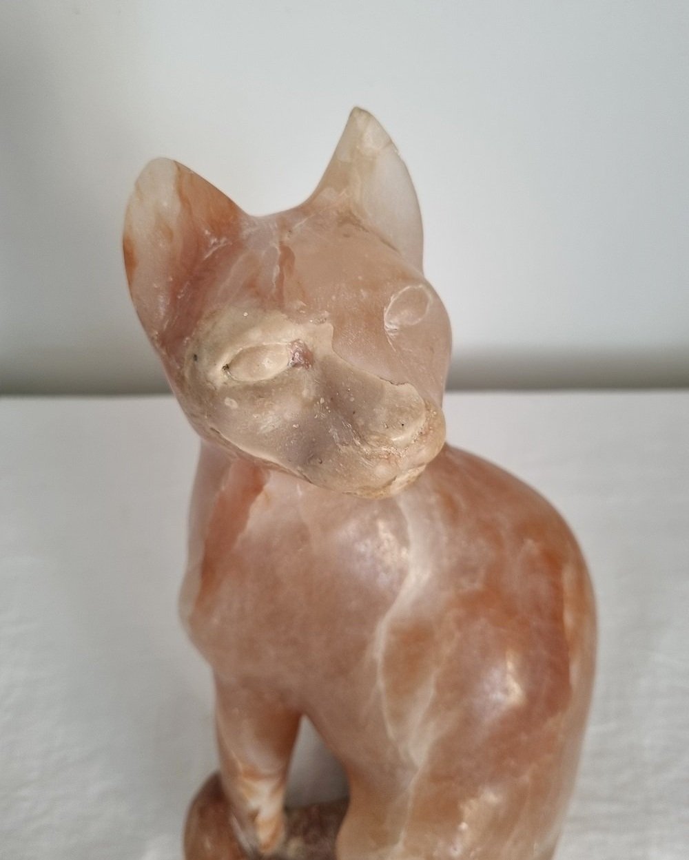 Vintage, heavy hand carved soft pink alabaster cat with striking natural grain and smooth lines.