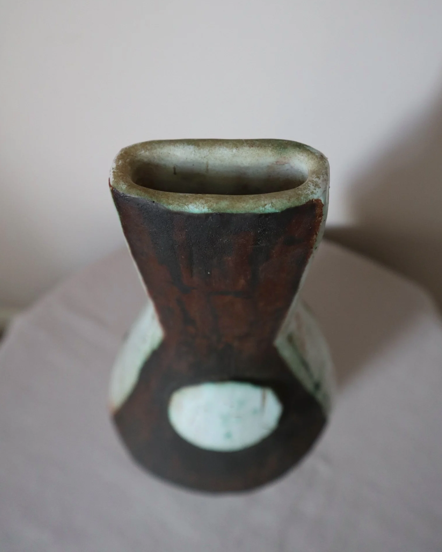 Vintage hand-built ceramic Brutalist art vase, featuring an abstract, asymmetrical design with textured white, dark brown, and subtle green glazes.