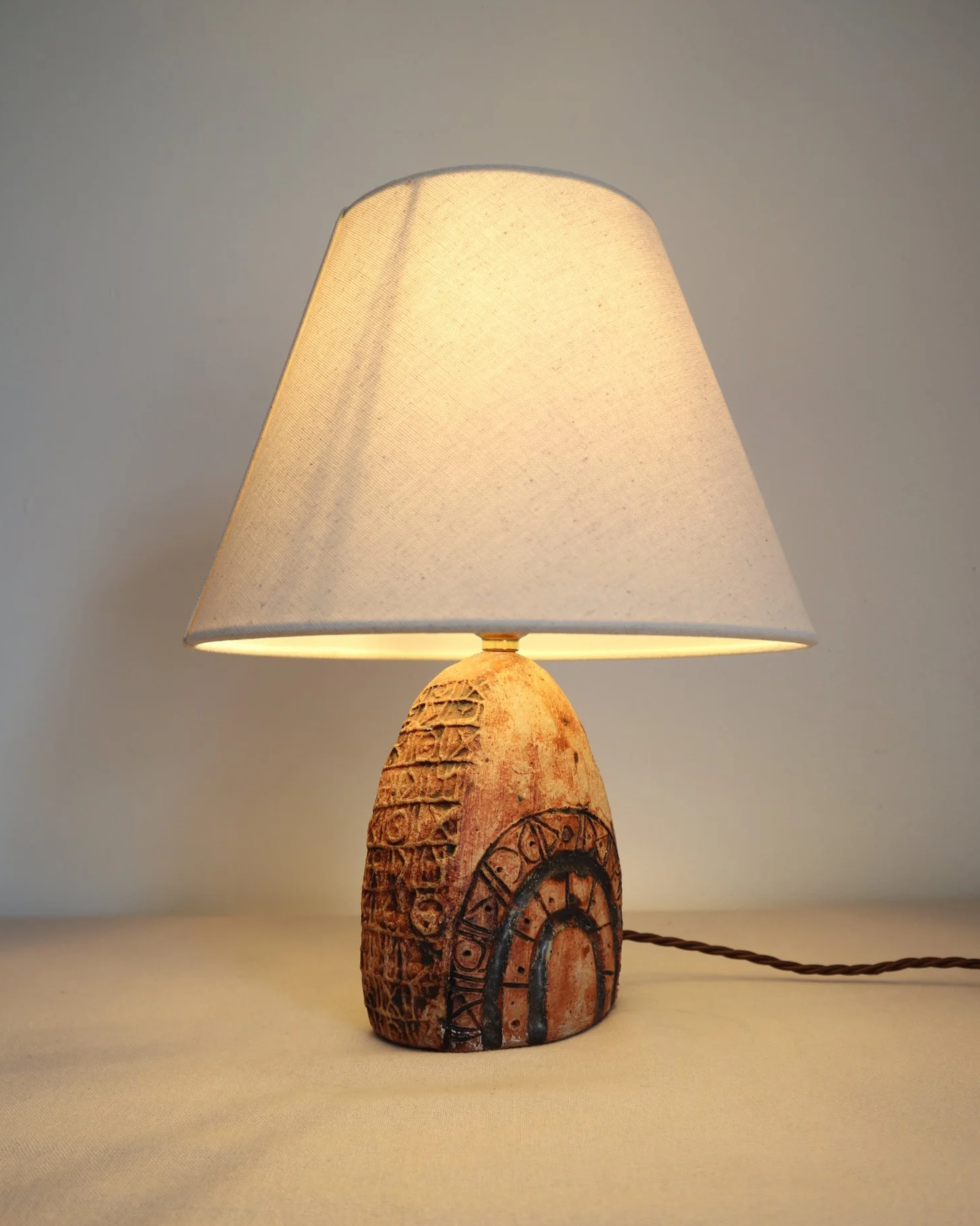 Small Brutalist stoneware table lamp by British potter Bernard Rooke. With stamped, rune-like impressions. Circa 1970s.