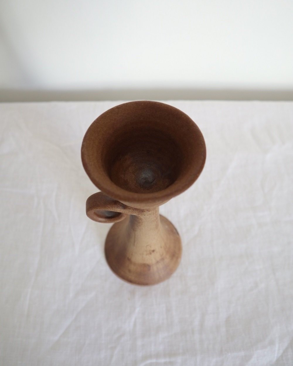 Rustic handmade studio pottery sculptural candleholder with curled circular handle.
