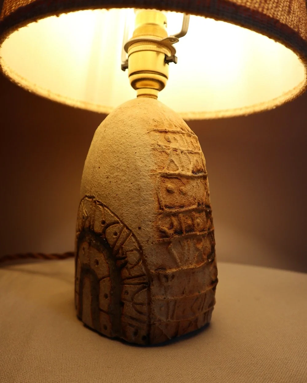 Small Brutalist stoneware table lamp by British potter Bernard Rooke. With stamped, rune-like impressions. Circa 1970s.