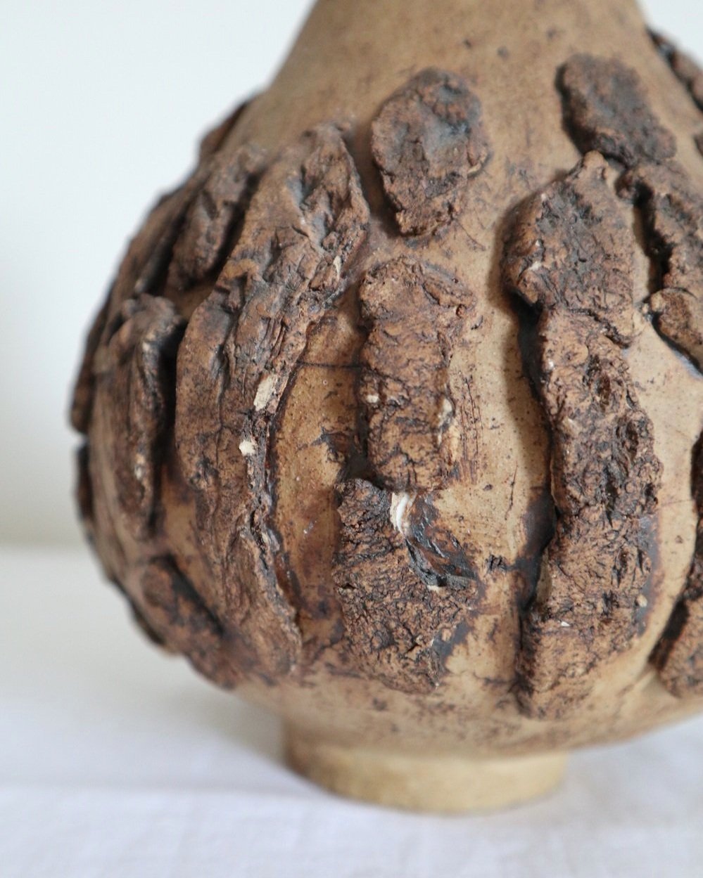 Studio pottery brown ceramic decorative vase with textured, tree bark effect decorations and a tapered neck. Age unknown.