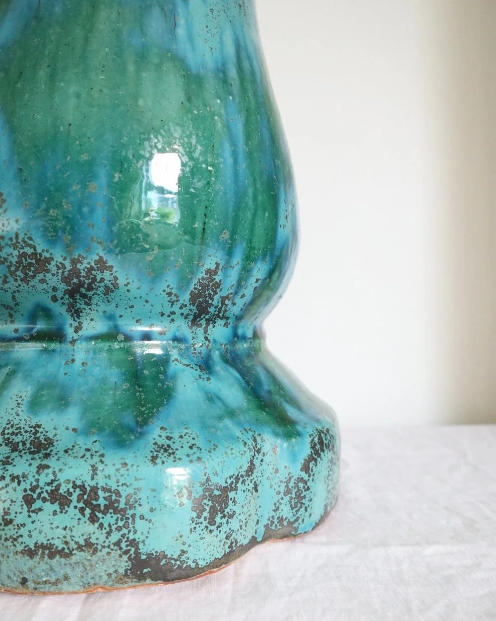 Art pottery ceramic jardiniere plant stand with mottled turquoise blue / green glossy drip glaze and speckled metallic grey detailing.
