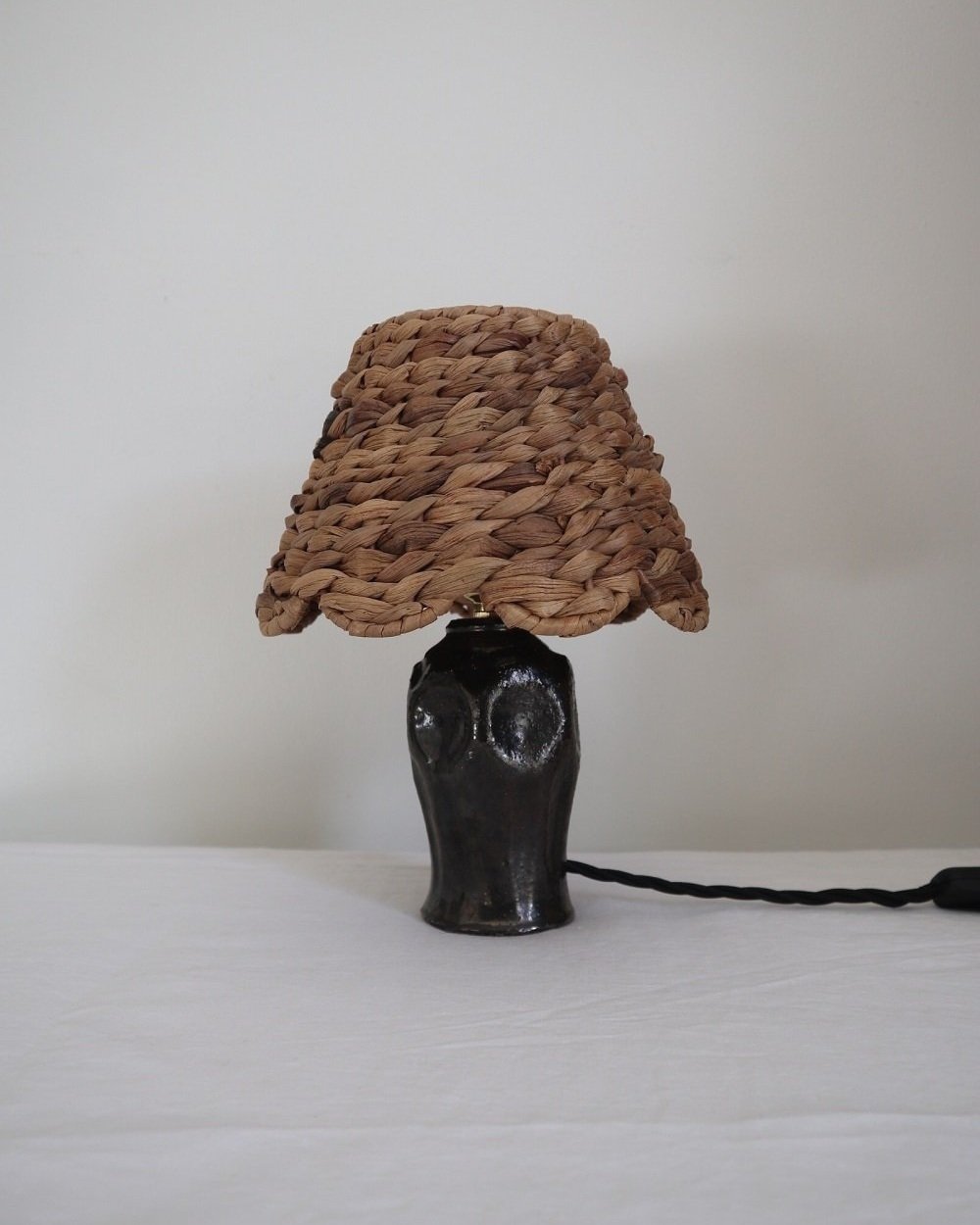 Small metallic deep brown/black glaze studio pottery ceramic table lamp with new, woven raffia scallop shape shade.