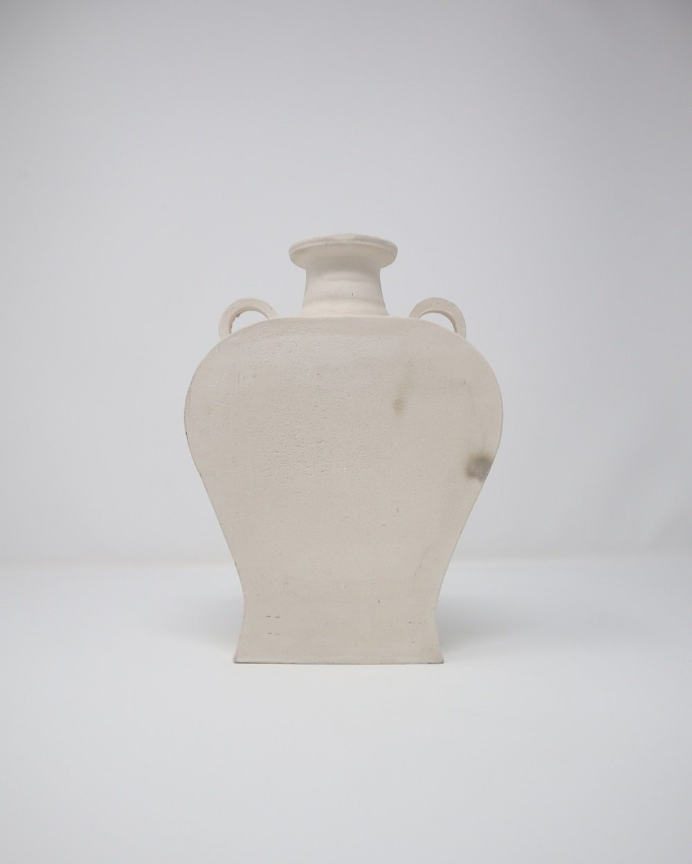 Pair of sculptural flat, matt white, untreated clay vases of simple form.