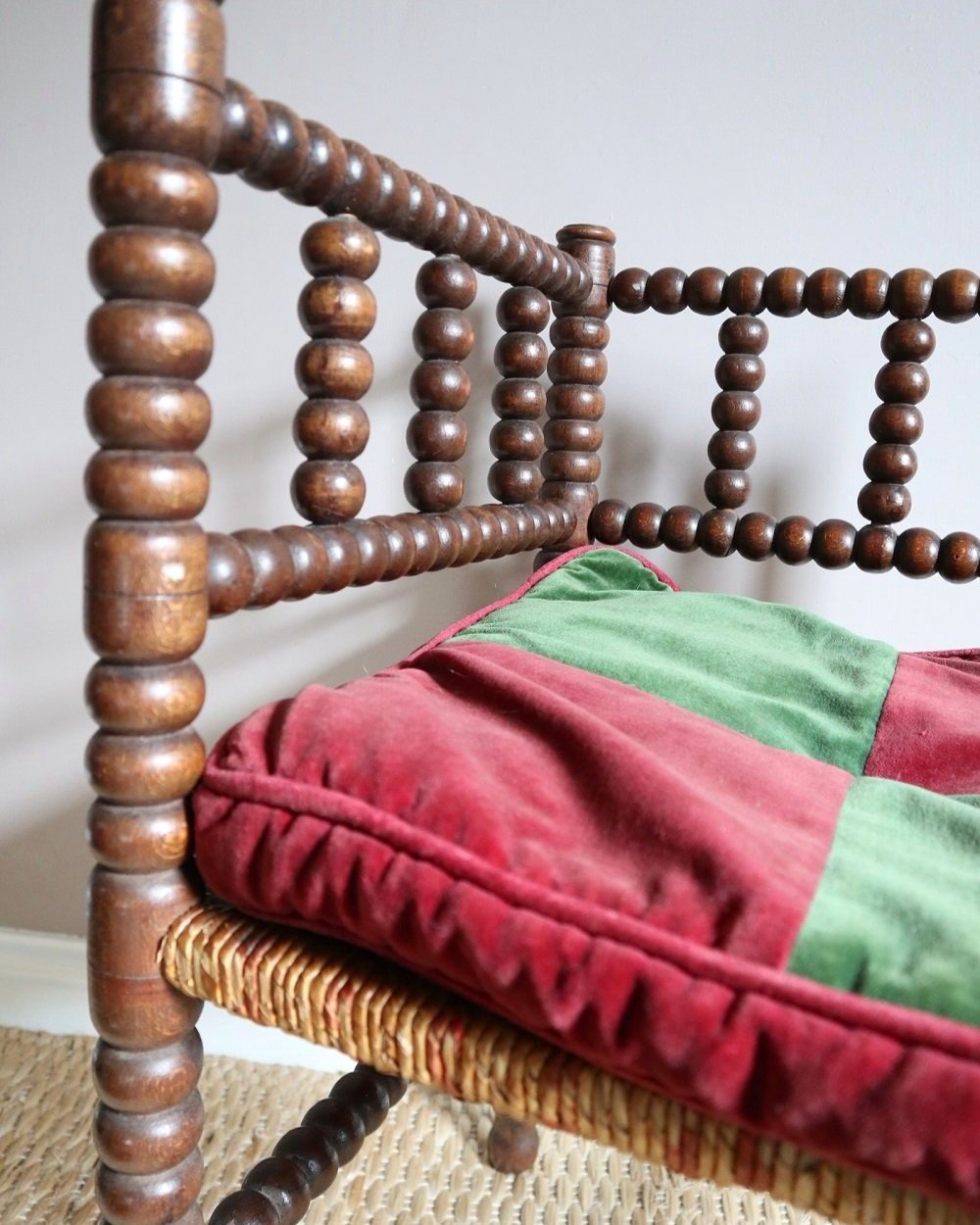 Characterful antique bobbin corner chair with interwoven red and natural rush seat and charming green and red velvet seat cushion. Circa 19th Century.