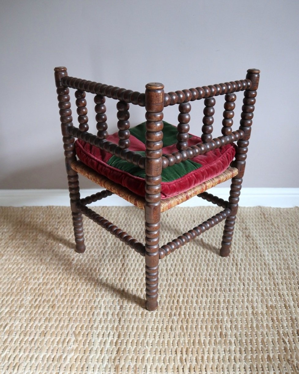 Characterful antique bobbin corner chair with interwoven red and natural rush seat and charming green and red velvet seat cushion. Circa 19th Century.