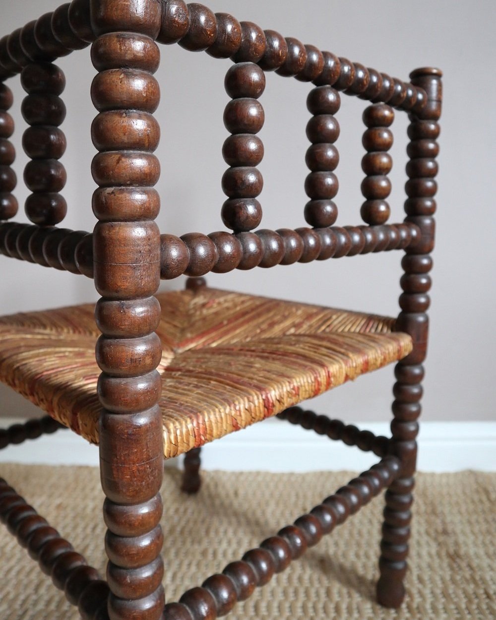 Characterful antique bobbin corner chair with interwoven red and natural rush seat and charming green and red velvet seat cushion. Circa 19th Century.