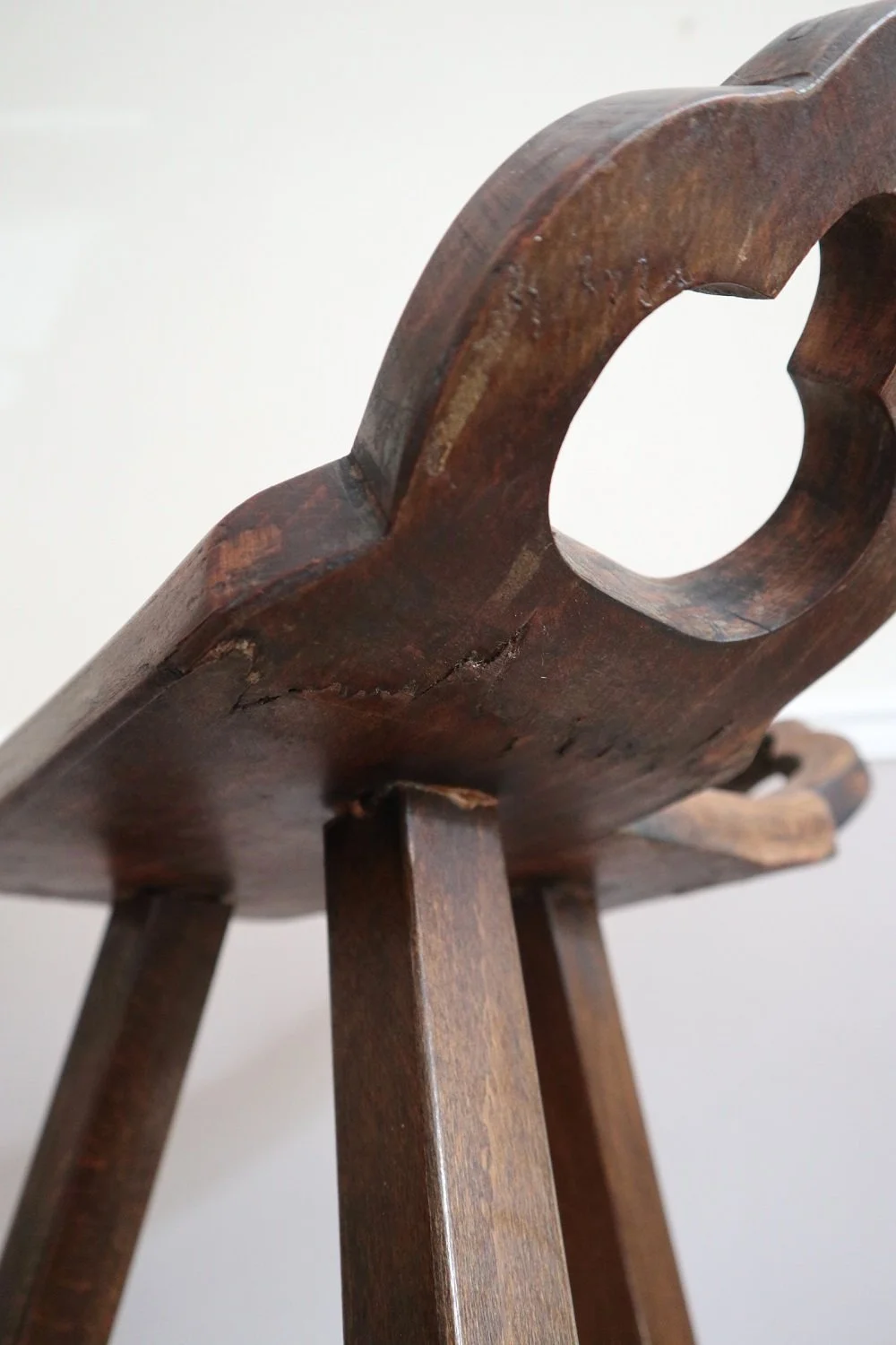 Pair of 1970s Brutalist Spanish style wooden tripod bar stools with hammered iron footrests and curved, carved seats.