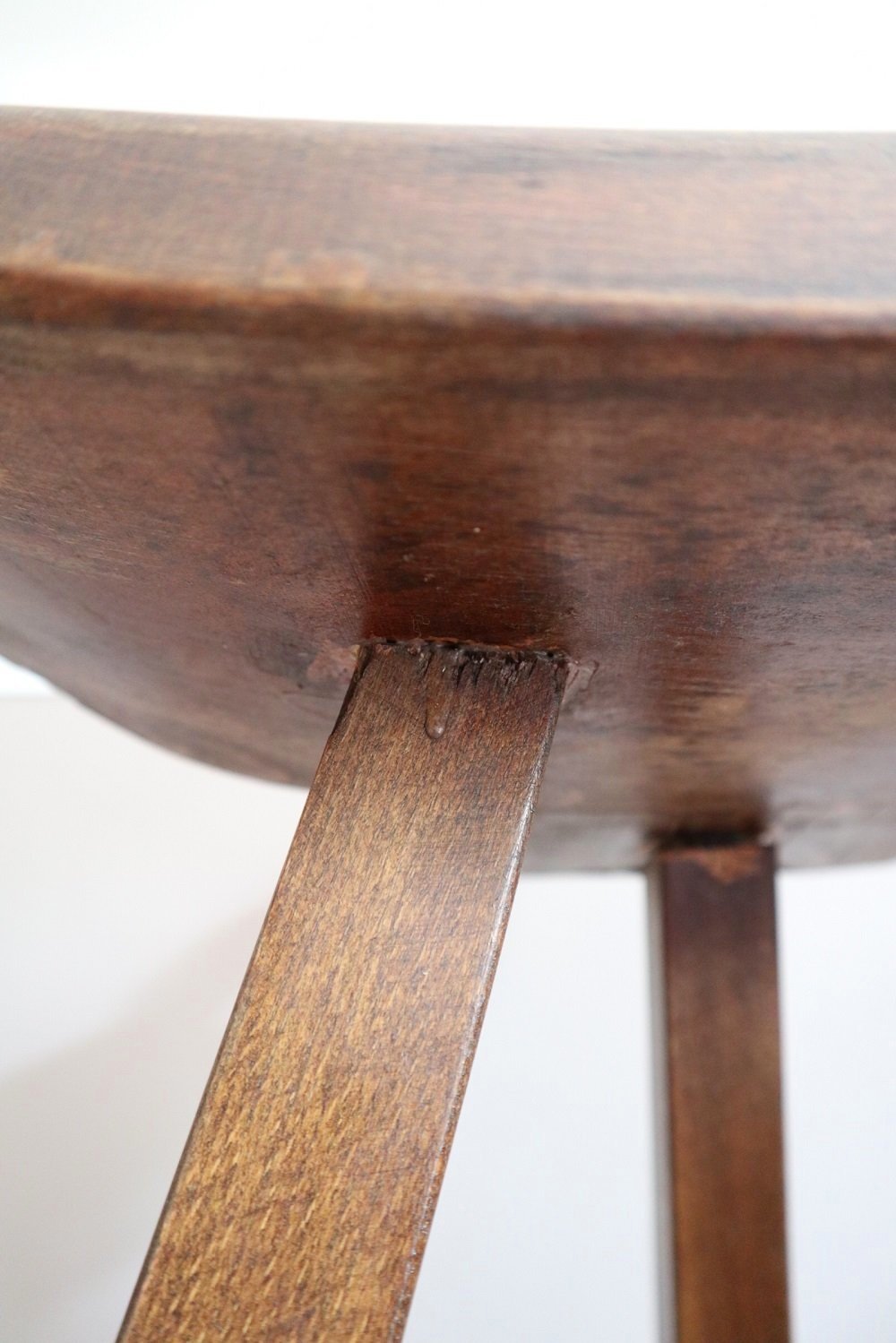 Pair of 1970s Brutalist Spanish style wooden tripod bar stools with hammered iron footrests and curved, carved seats.