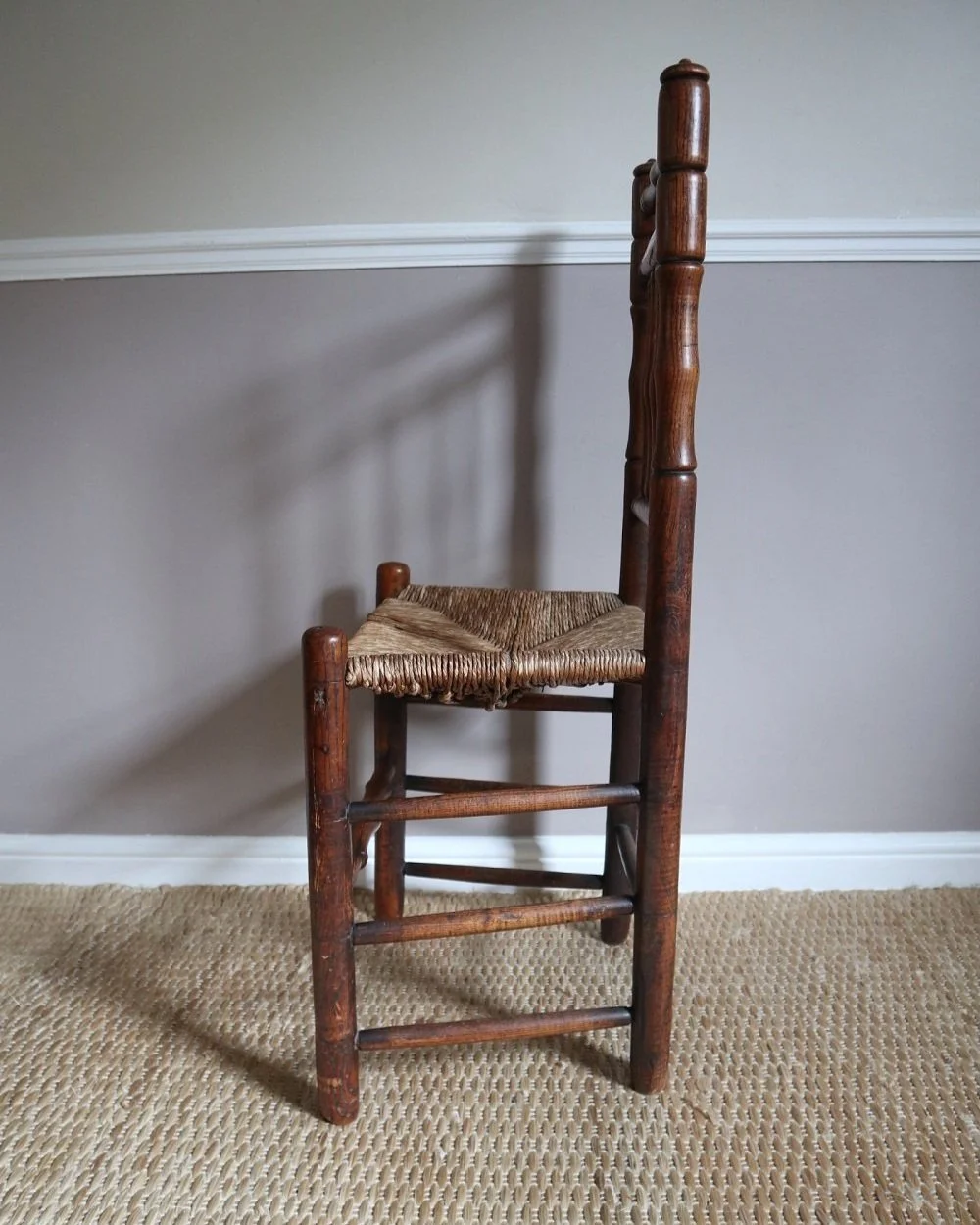 A charming antique, Victorian era spindle back wooden chair with a woven rush seat. The warm toned, turned wood frame has aged beautifully.
