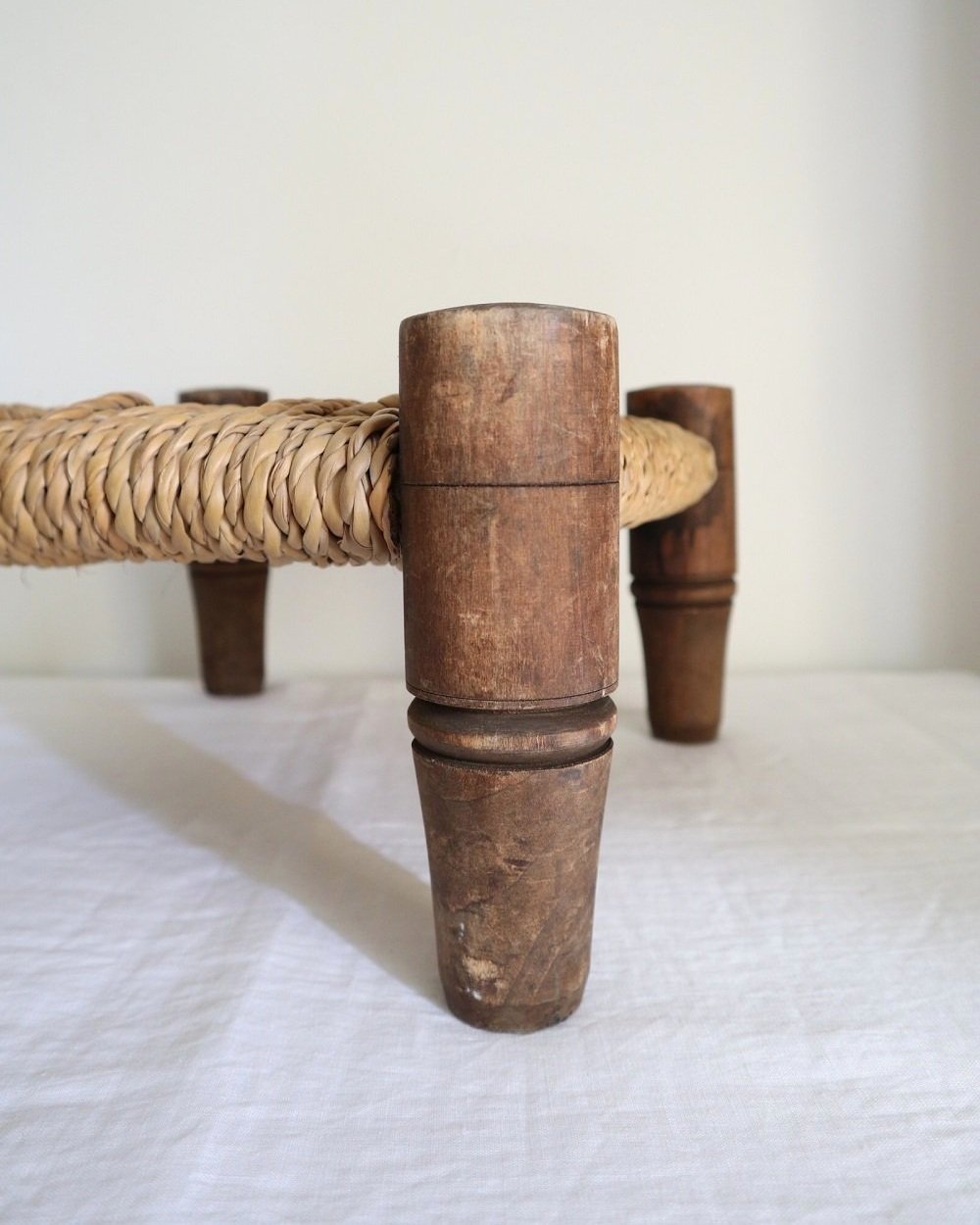 20th Century small woven rope footstool with thick turned wooden legs. In the style of Audoux & Minnet, France.