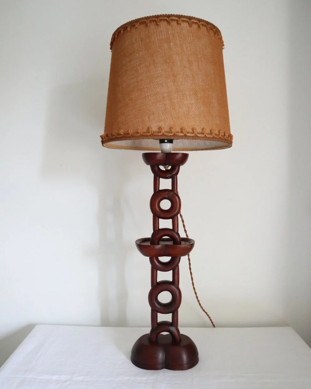 Tall mid century sculptural hand carved warm wooden totem table lamp with original hessian lampshade. Circa 1960s.