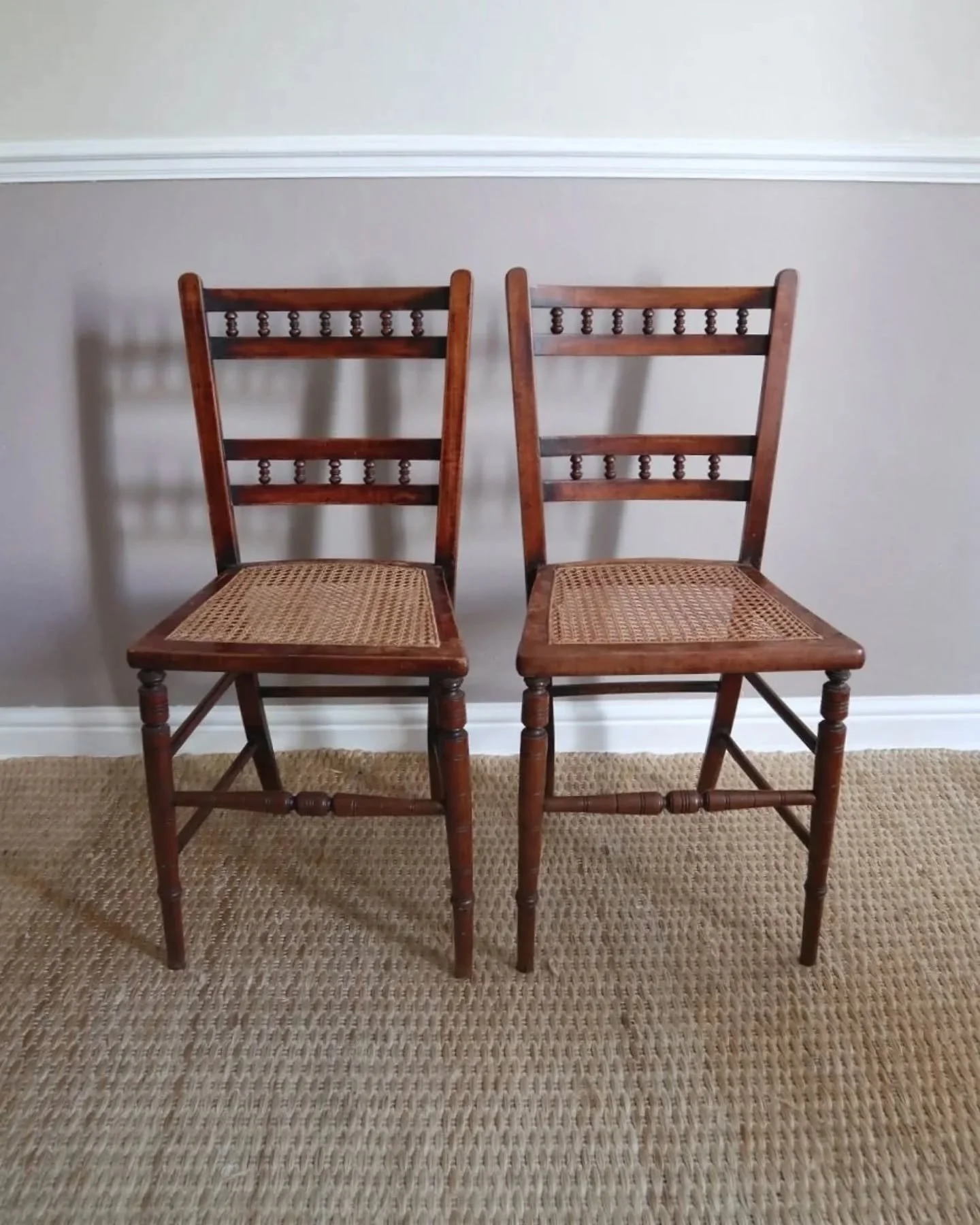 New to Peach ~ A pair of elegant wooden dining chairs with rattan seats and turned wood legs. 

In vintage condition with signs of age and wear, both have light watermarks to the seats but the rattan is in fantastic condition. One chair has a previou