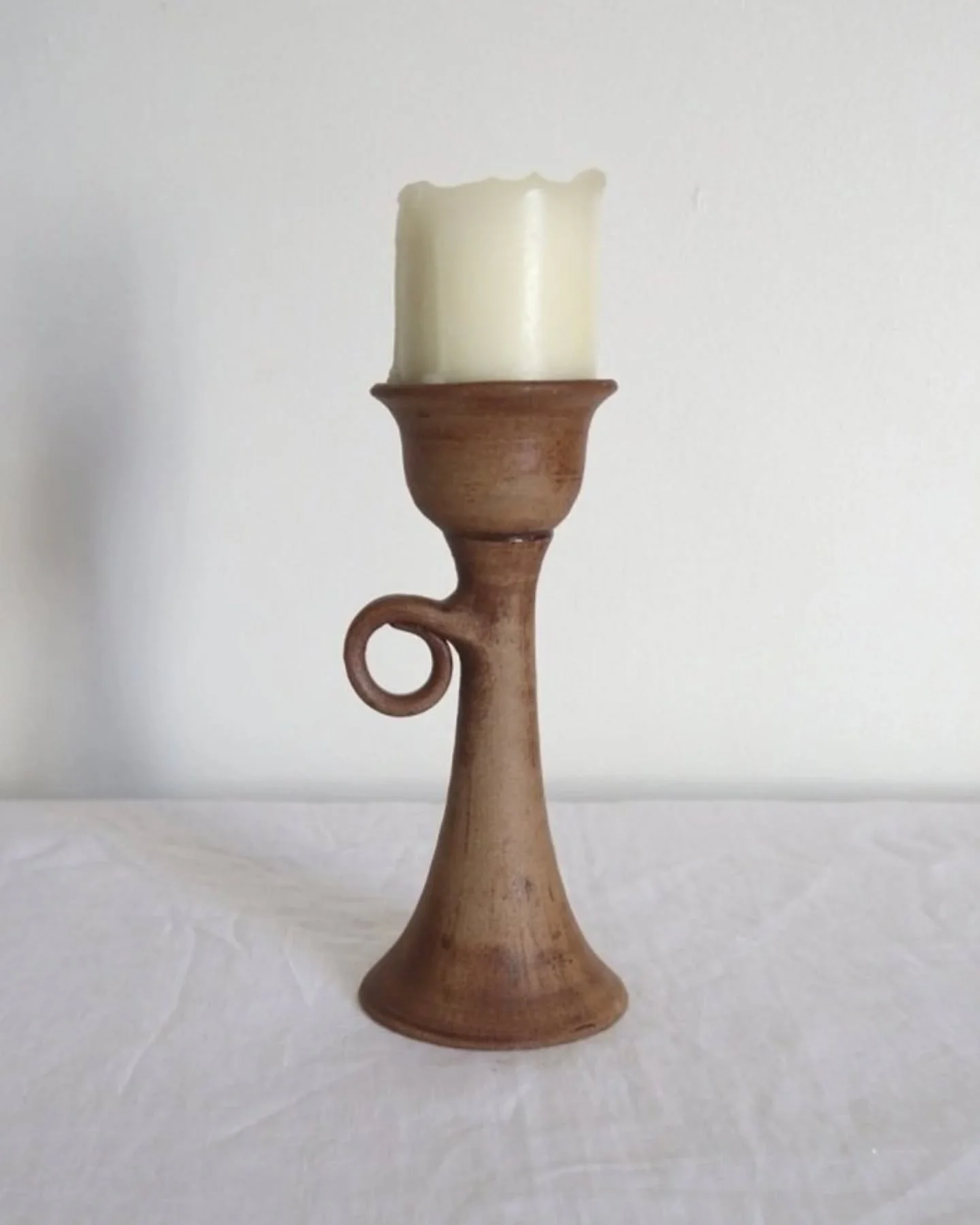 Available online ~ Rustic handmade studio pottery sculptural candleholder with curled circular handle.

No makers marks.

Candle not included.

8mm chip to base and some marks to bottom edge in manufacture.

H19cm / Base Diam 8.5cm / Top Diam 7cm