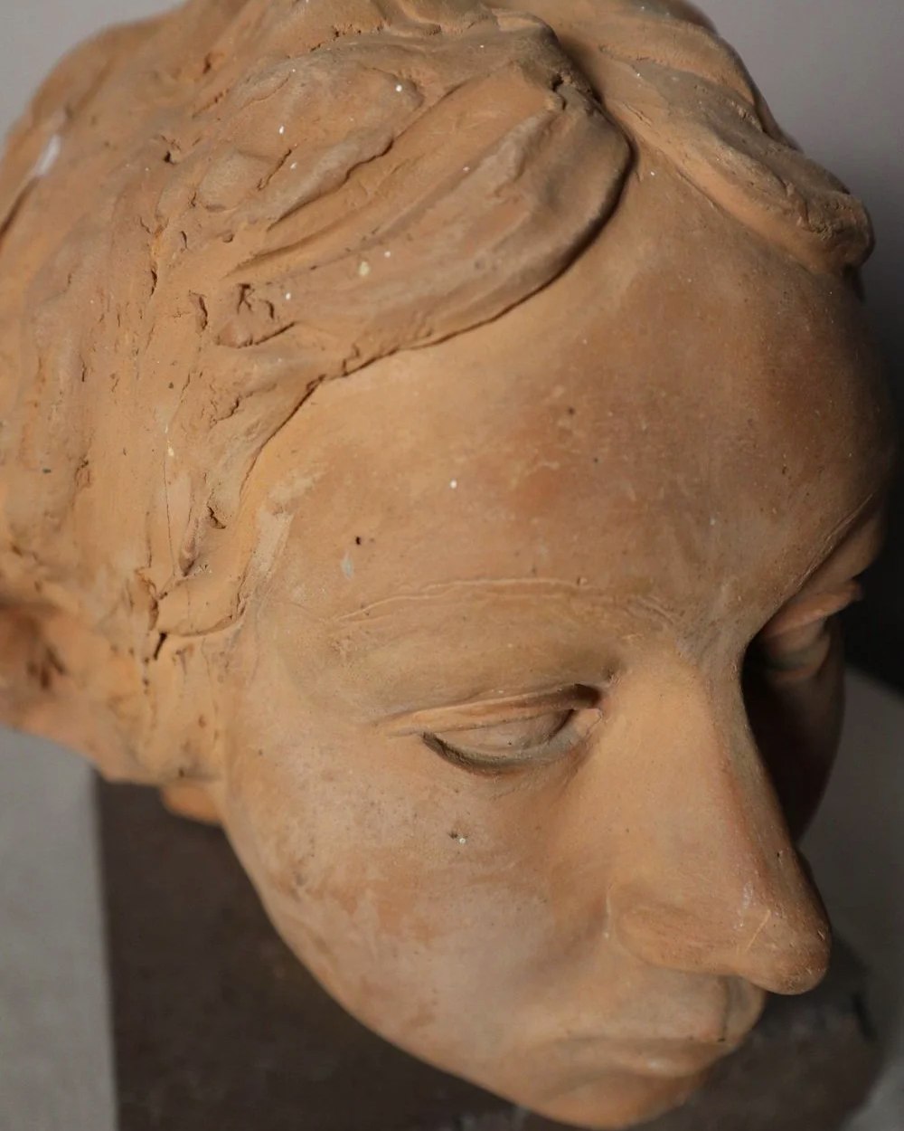 A signed, 20th century art studio terracotta female bust with stone display plinth.
