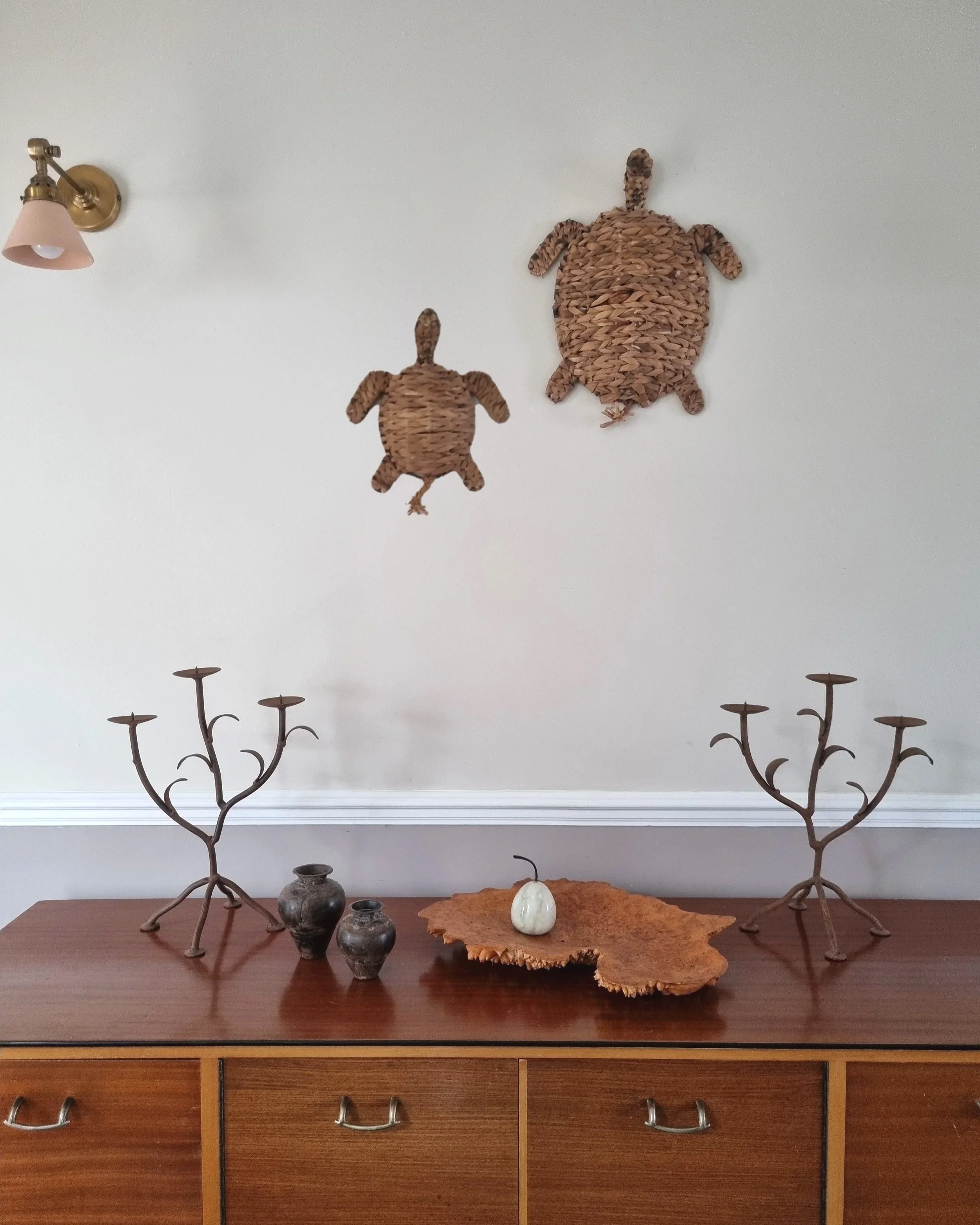 Pair of mid-century, sculptural hand crafted wrought iron 3-arm candle holders with decorative leaves and four footed base.