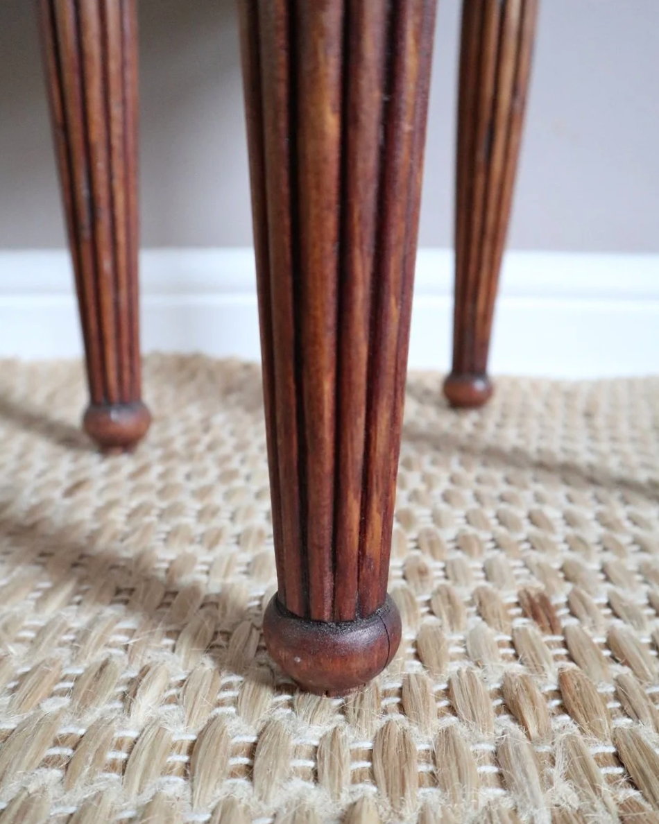 Antique Regency style carved wooden stool with four reeded tapered legs and dusky pink patterned upholstered seat.