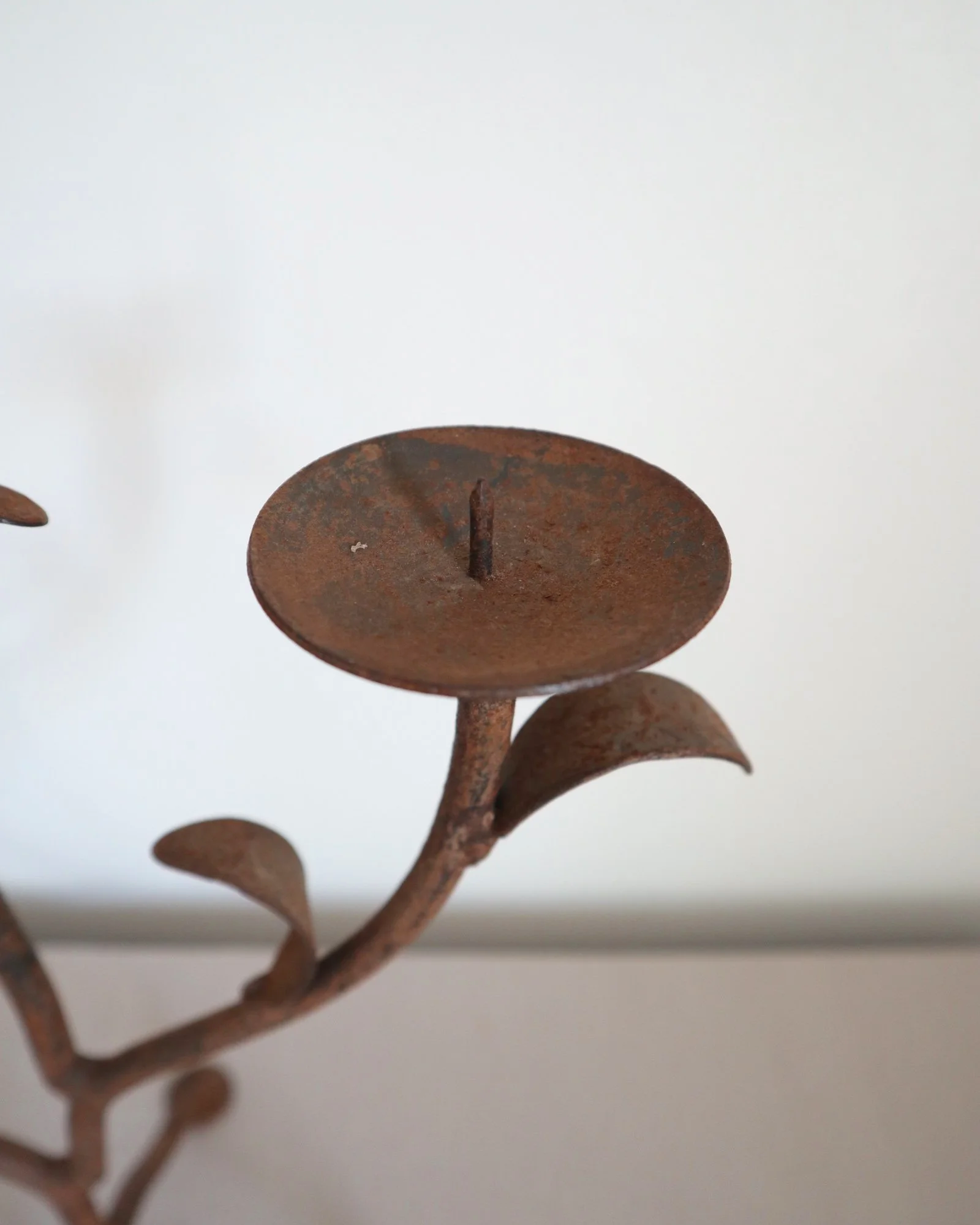 Pair of mid-century, sculptural hand crafted wrought iron 3-arm candle holders with decorative leaves and four footed base.