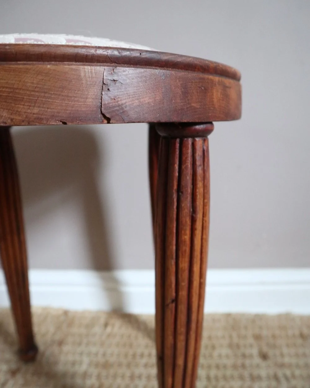 Antique Regency style carved wooden stool with four reeded tapered legs and dusky pink patterned upholstered seat.