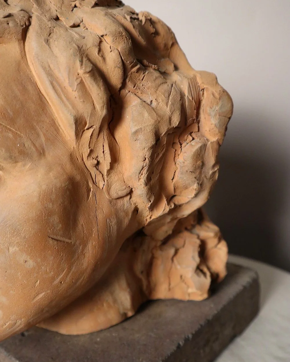 A signed, 20th century art studio terracotta female bust with stone display plinth.
