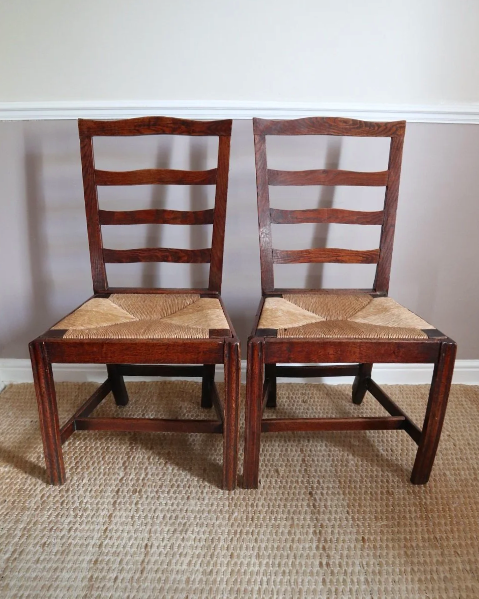 Pair of sculptural rustic oak ladder back dining chairs with rush seats, circa 1930s.