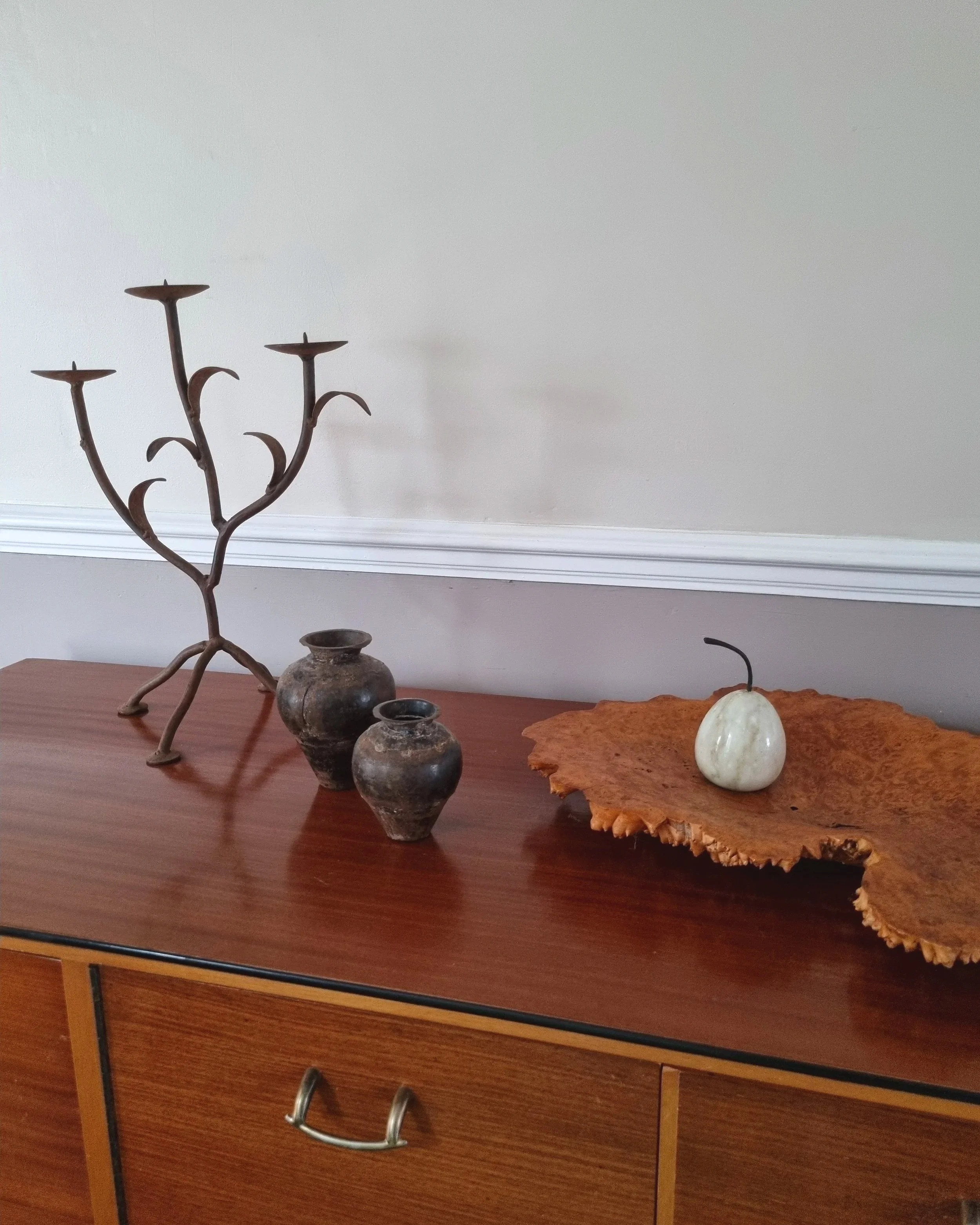 Pair of mid-century, sculptural hand crafted wrought iron 3-arm candle holders with decorative leaves and four footed base.