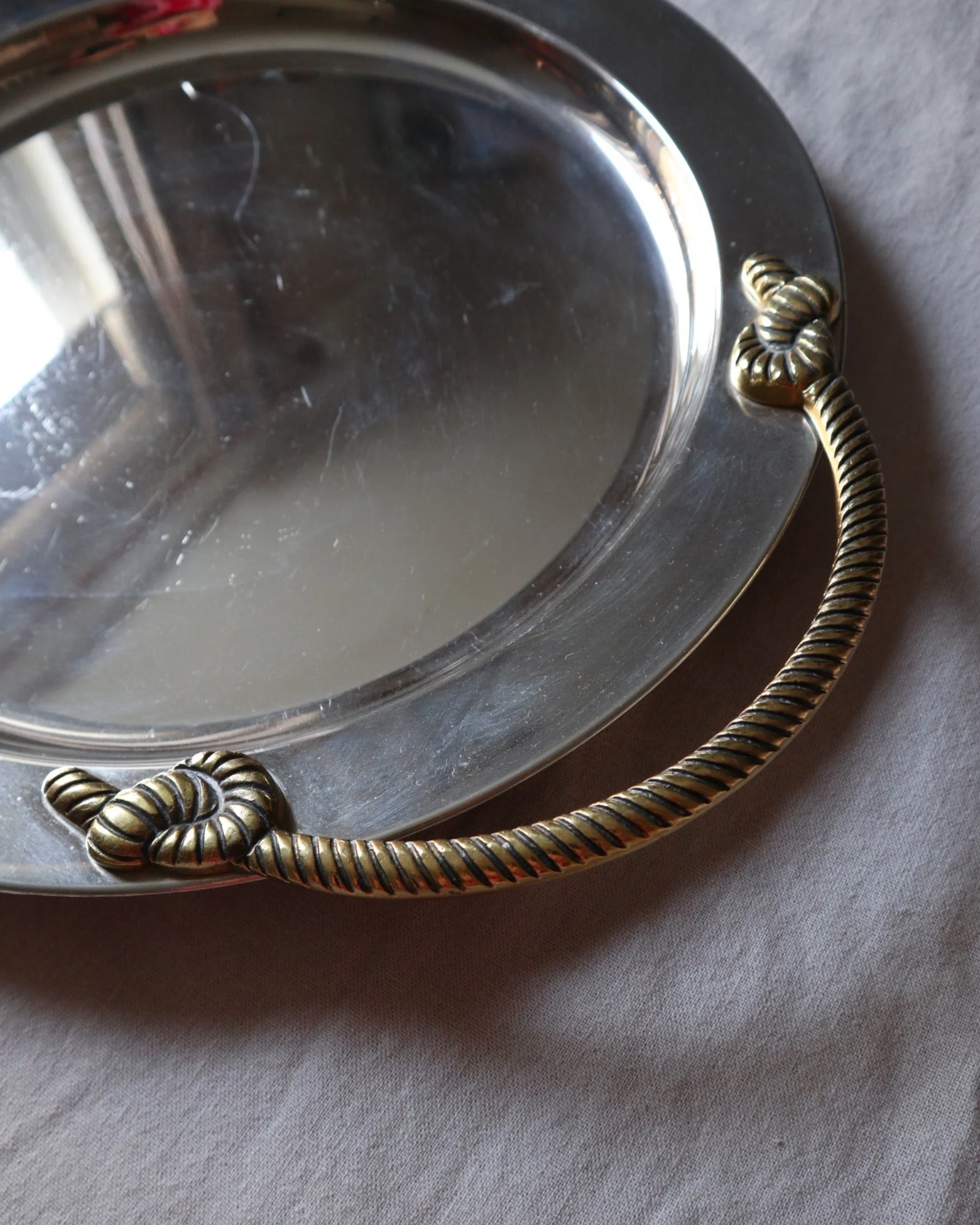 Large mid century circular shiny metal serving tray with elegant brass rope design handles.