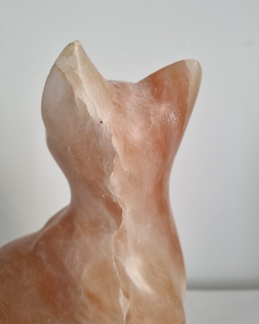 Vintage, heavy hand carved soft pink alabaster cat with striking natural grain and smooth lines.