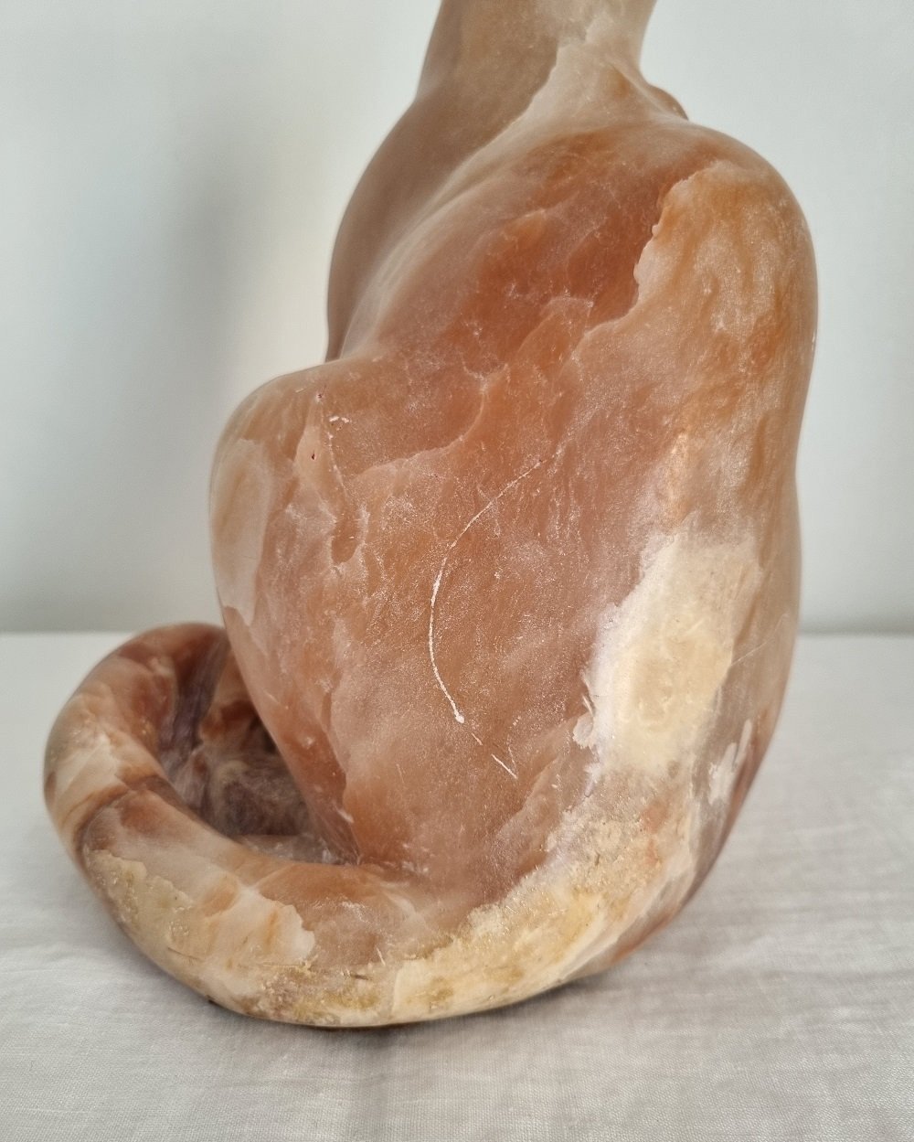 Vintage, heavy hand carved soft pink alabaster cat with striking natural grain and smooth lines.
