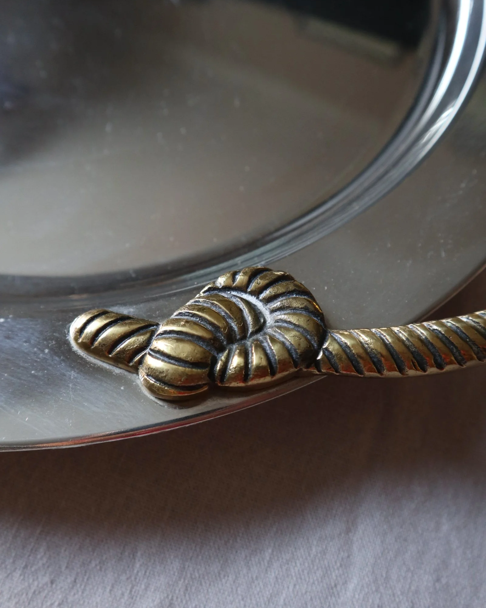 Large mid century circular shiny metal serving tray with elegant brass rope design handles.