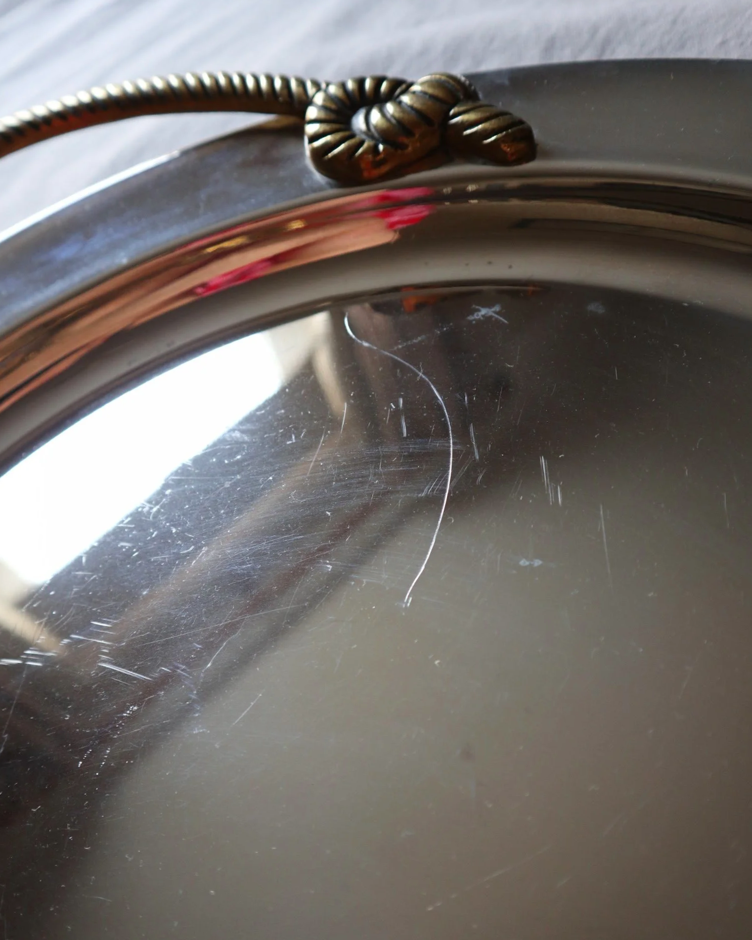 Large mid century circular shiny metal serving tray with elegant brass rope design handles.