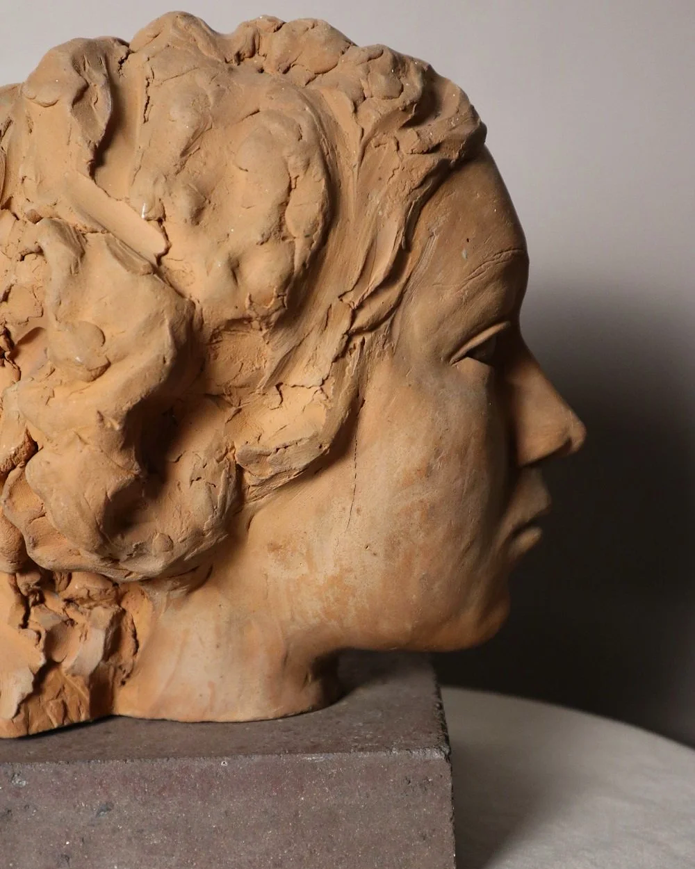 A signed, 20th century art studio terracotta female bust with stone display plinth.