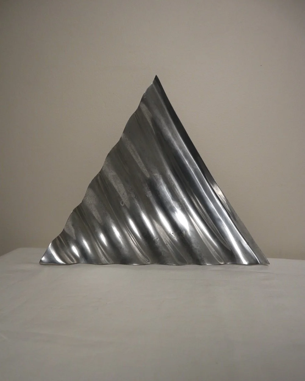 Large mid century, shiny cast aluminium triangular display dish with wavy edge.