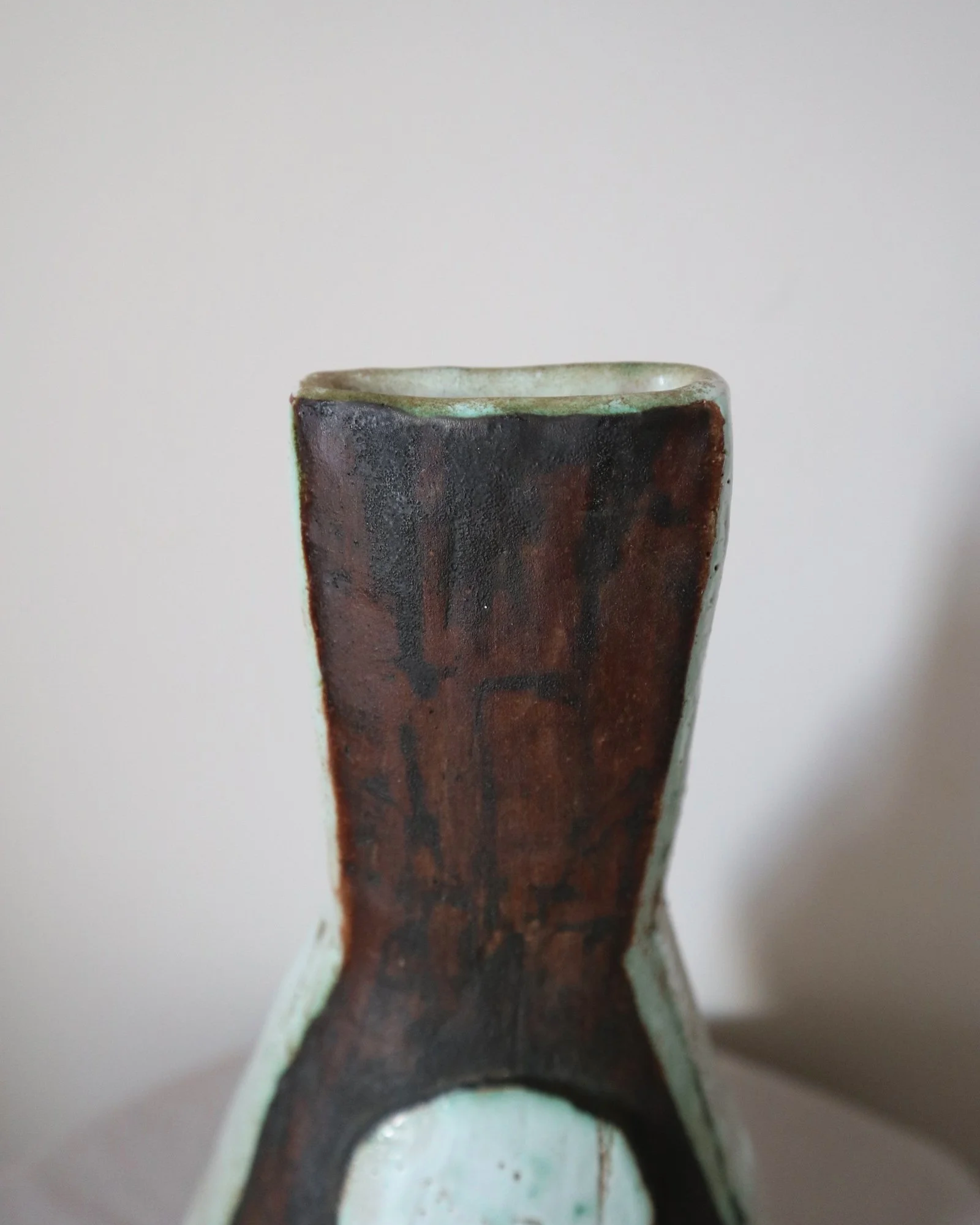 Vintage hand-built ceramic Brutalist art vase, featuring an abstract, asymmetrical design with textured white, dark brown, and subtle green glazes.