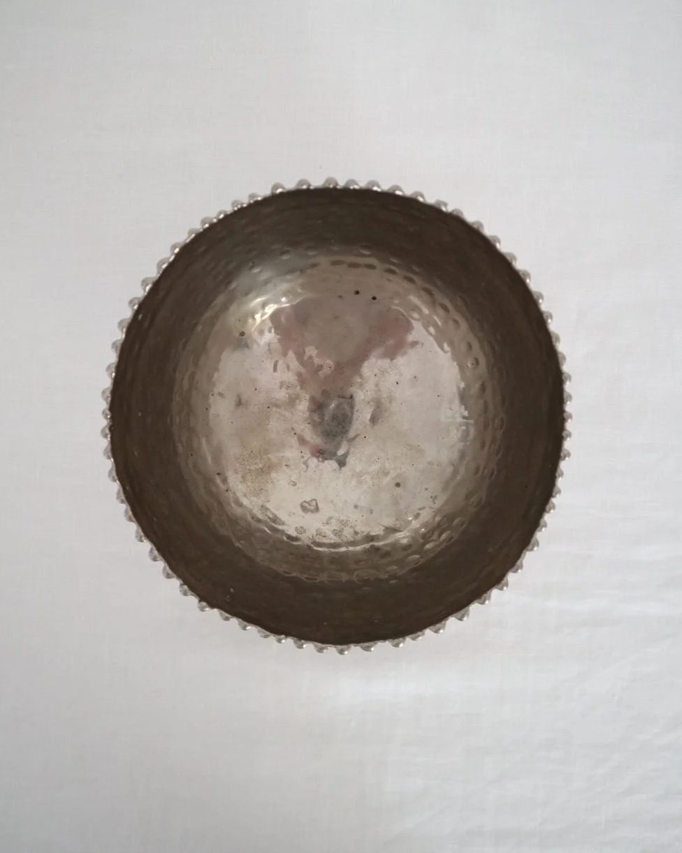 Small hammered metal lightweight circular dish with three ball feet and decorative beaded edging.