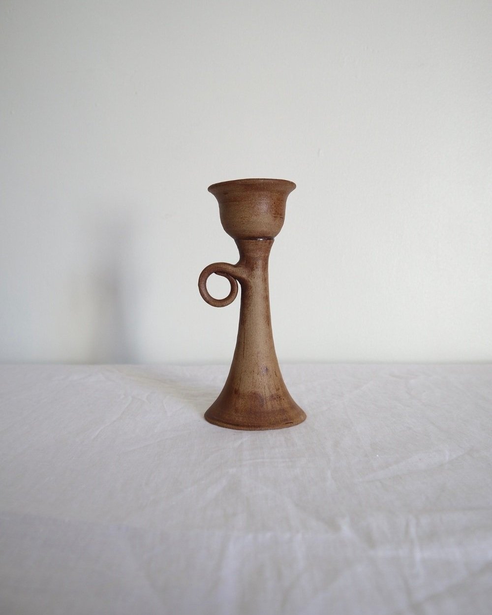 Rustic handmade studio pottery sculptural candleholder with curled circular handle.