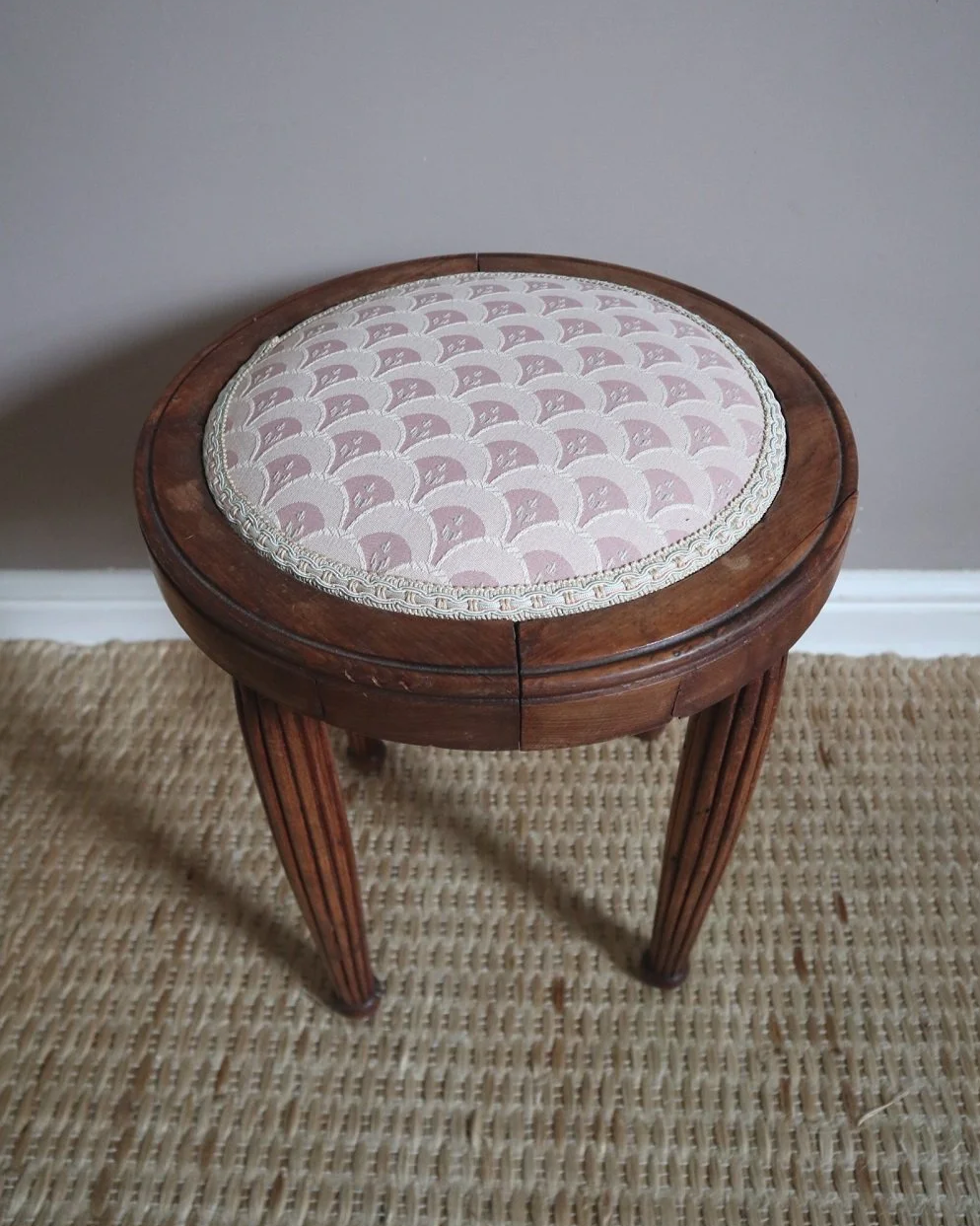 Antique Regency style carved wooden stool with four reeded tapered legs and dusky pink patterned upholstered seat.
