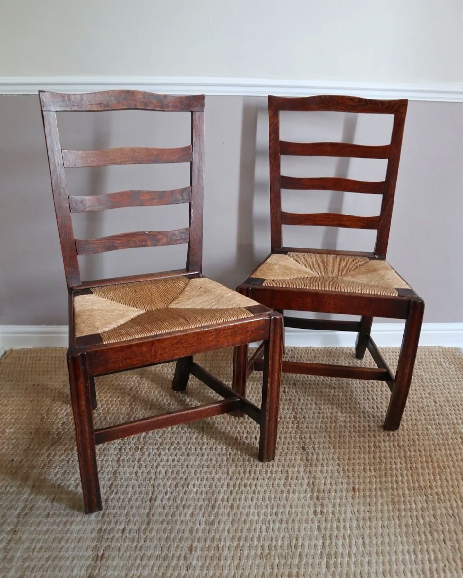 Pair of sculptural rustic oak ladder back dining chairs with rush seats, circa 1930s.