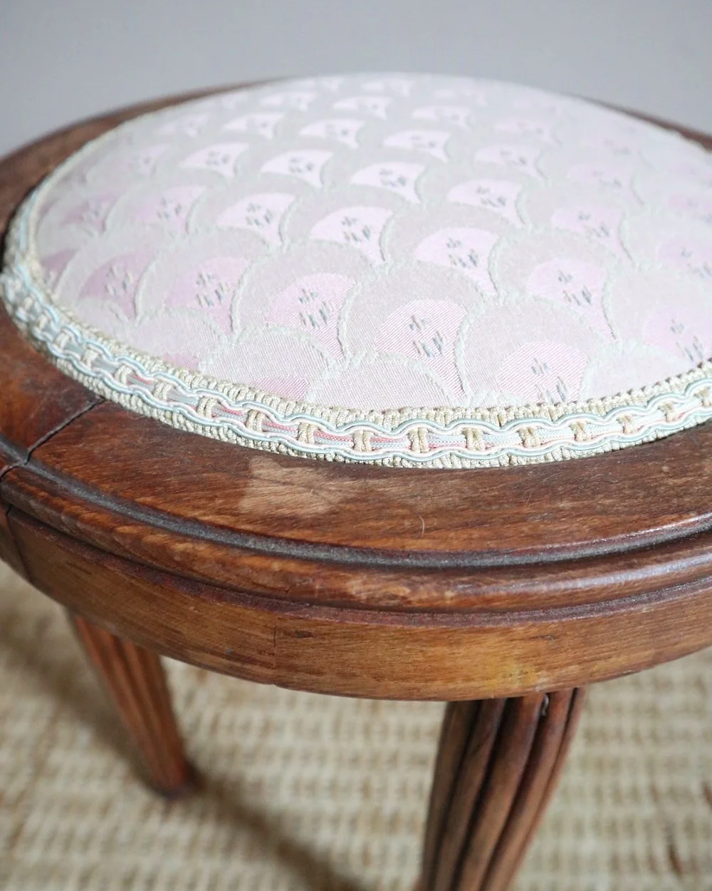 Antique Regency style carved wooden stool with four reeded tapered legs and dusky pink patterned upholstered seat.