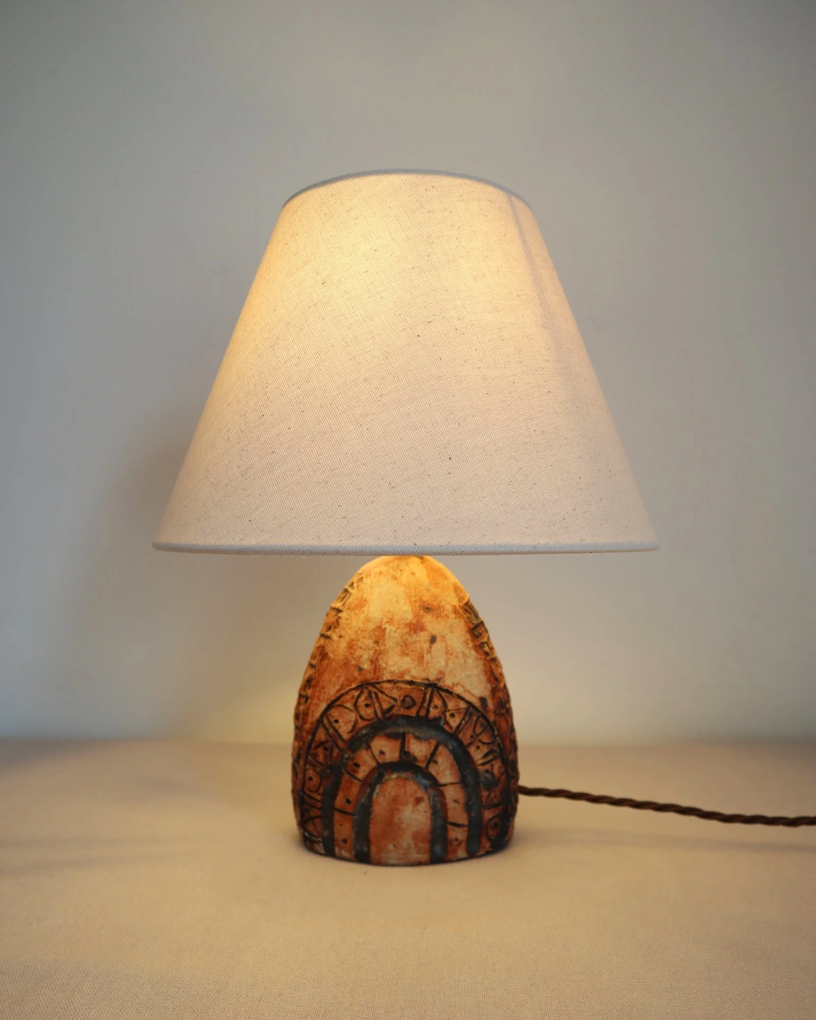 Small Brutalist stoneware table lamp by British potter Bernard Rooke. With stamped, rune-like impressions. Circa 1970s.