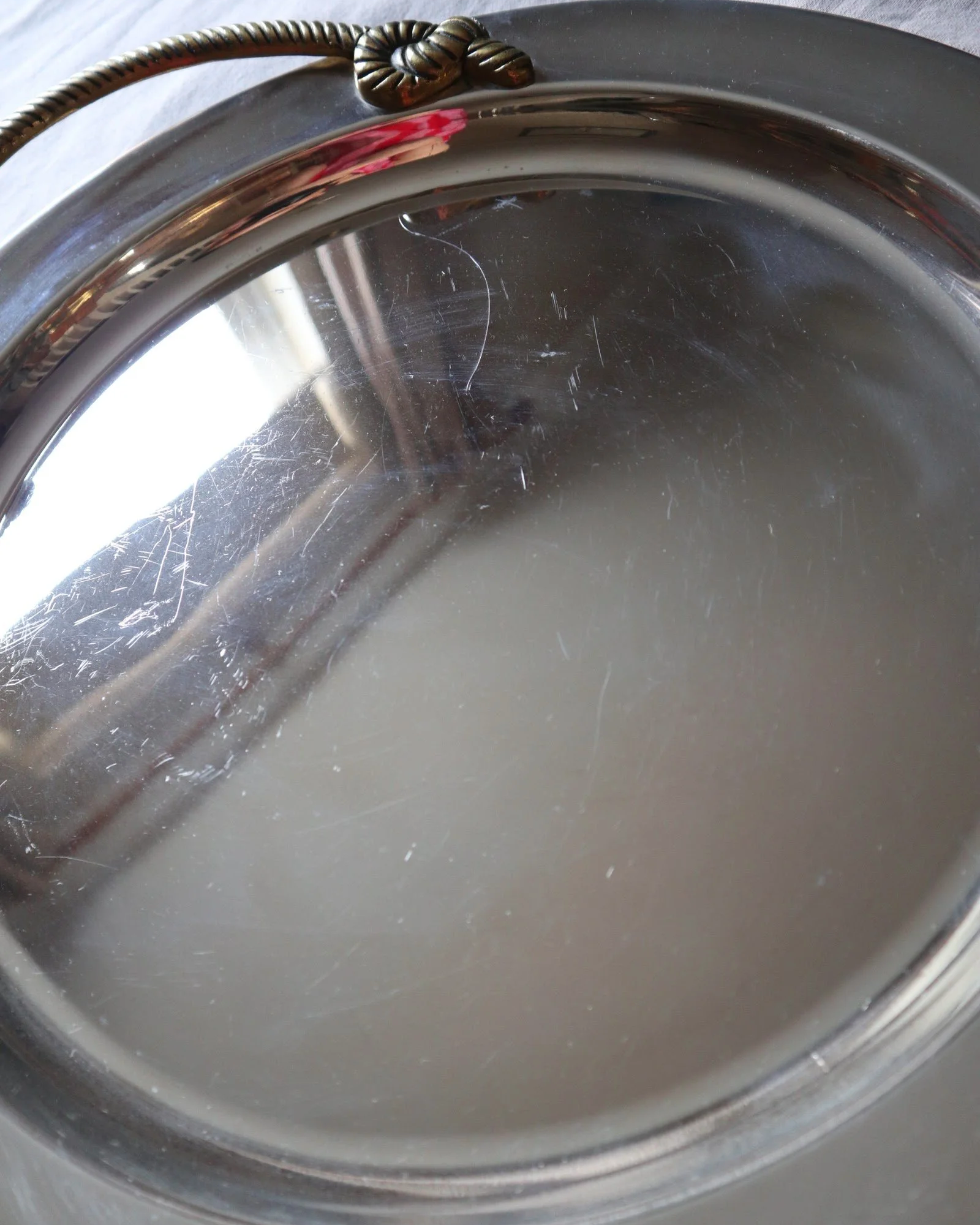 Large mid century circular shiny metal serving tray with elegant brass rope design handles.