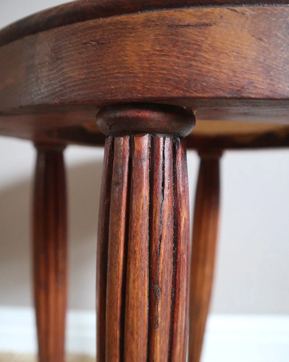 Antique Regency style carved wooden stool with four reeded tapered legs and dusky pink patterned upholstered seat.
