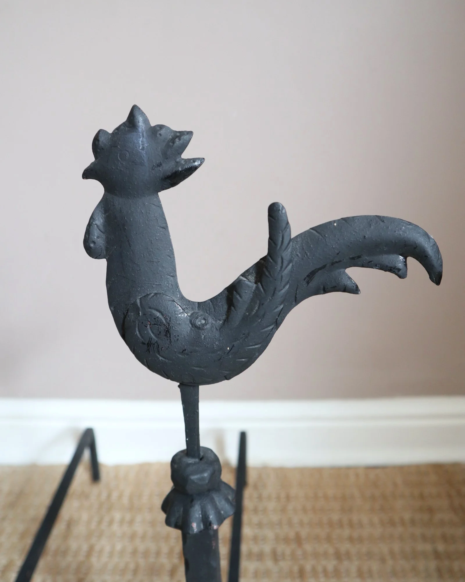 Pair of black wrought-iron andirons or firedogs featuring stylized rooster finials, circa mid-20th century.